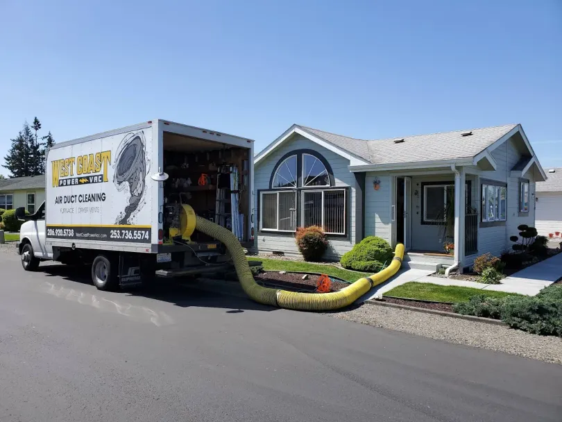 White truck connected to a blue house via a yellow hose, presumably for home improvement or cleaning.