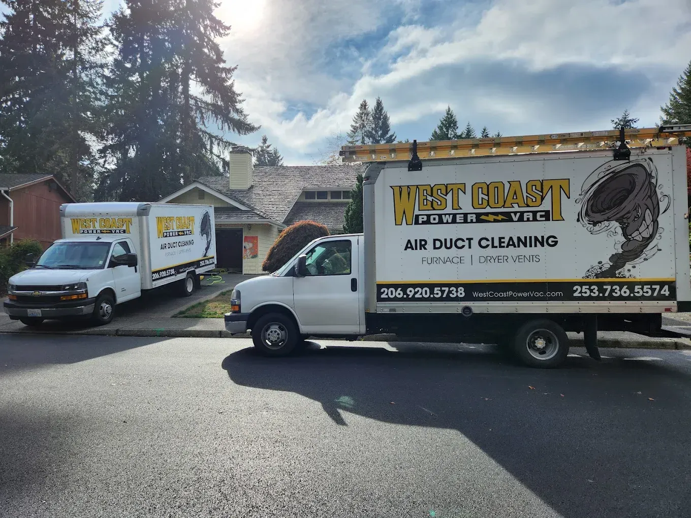 Two West Coast Power Vac trucks parked in front of a house; air duct cleaning services.