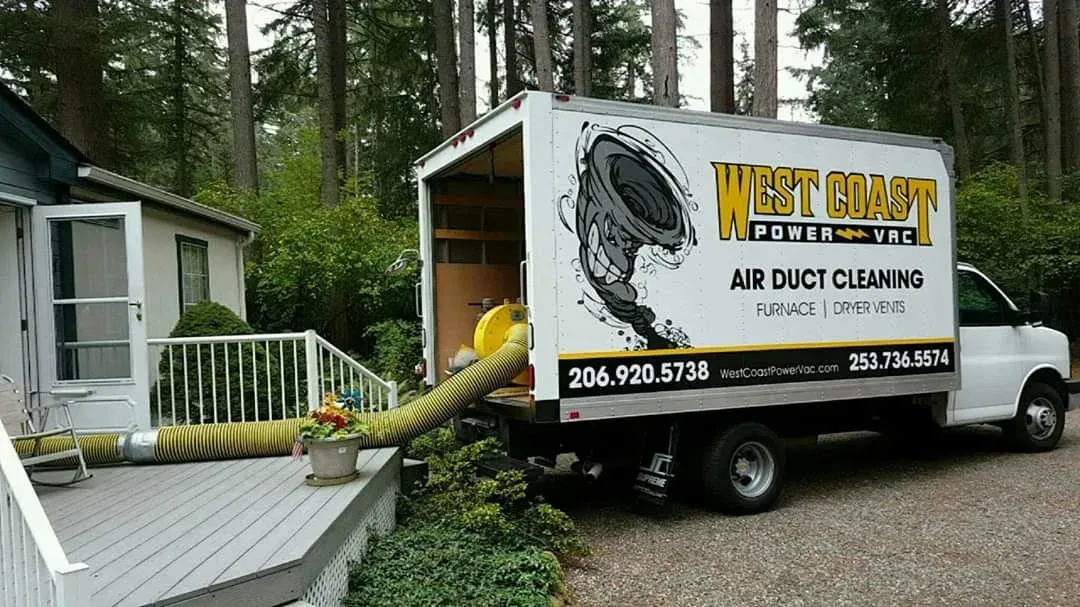 Truck from West Coast Air Duct Cleaning with hose attached to a house's deck, cleaning the air ducts.