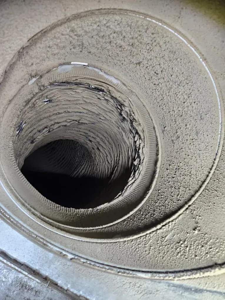 Dirty, dust-filled air vent with a spiral shape, covered in layers of dirt.