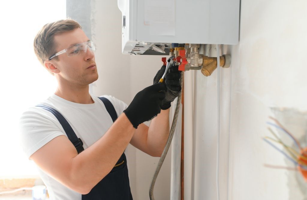 A man is fixing a boiler on a wall.