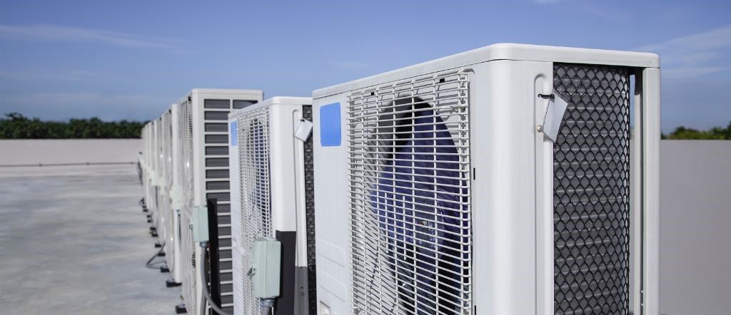 A row of air conditioners are lined up on a roof.