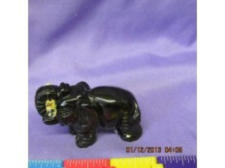 Black elephant figurine on a purple fabric background, with a yellow-tinted face.