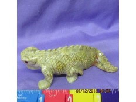 Green toy reptile figurine on a purple background with a red-and-blue ruler