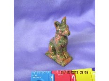 Small cat figurine on a purple cloth, standing on a base beside a blue measuring ruler.