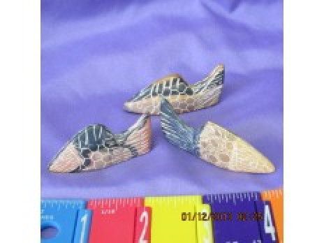 Three small seashells on purple fabric beside a ruler