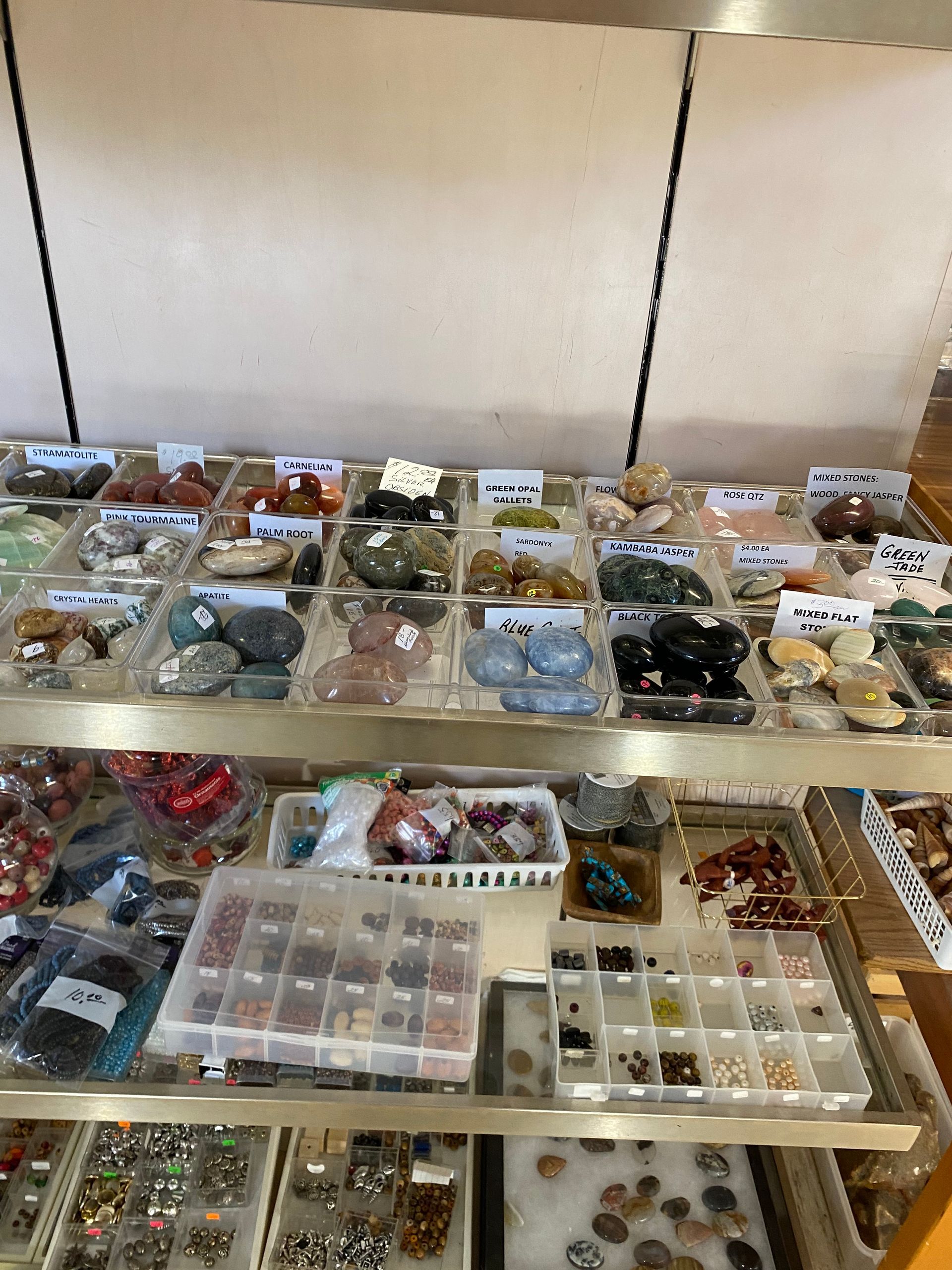 Display of assorted jewelry and trinkets in small trays on shelves at a market stall