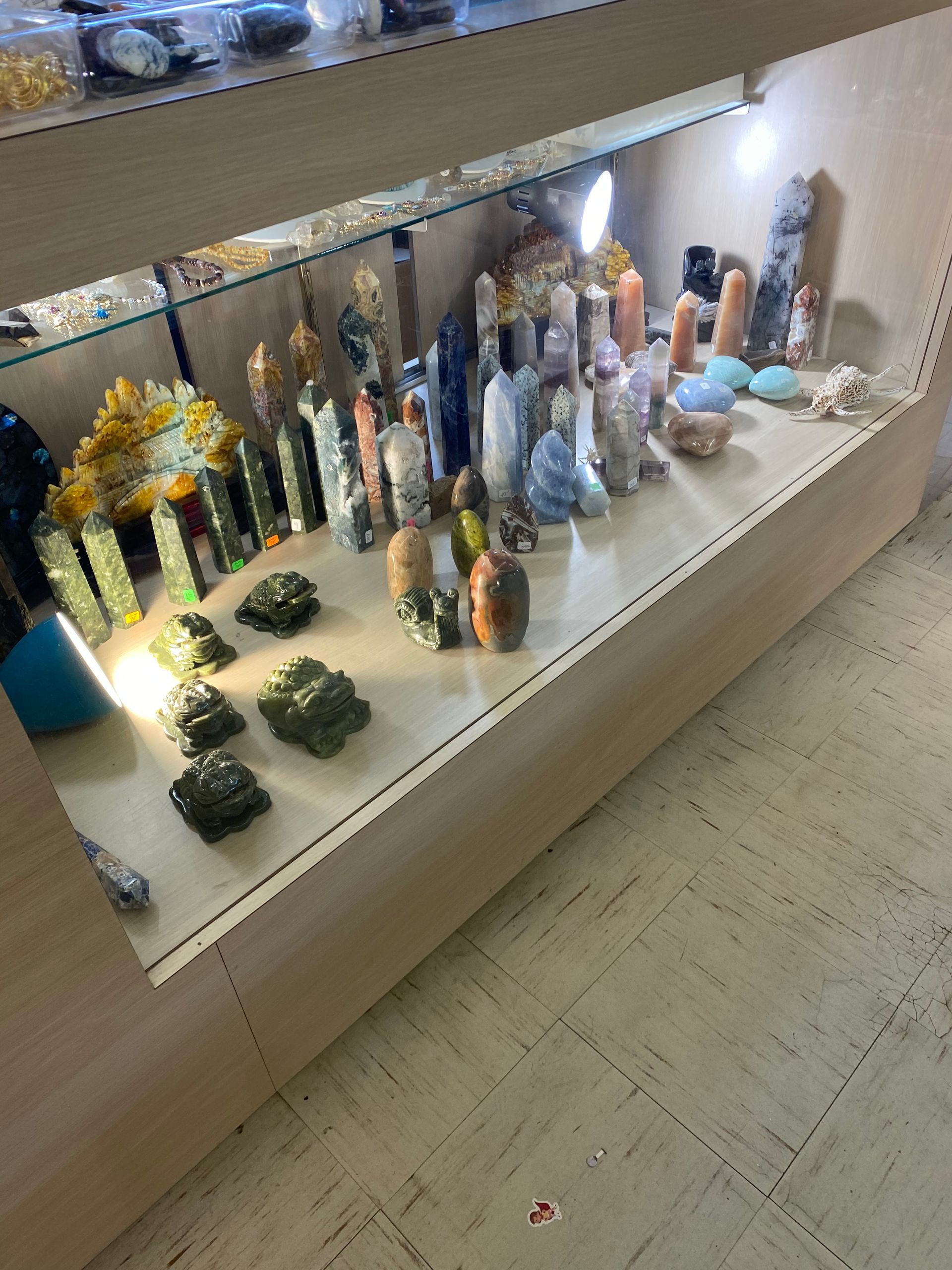Display of colorful decorative figurines on a shop shelf under bright lights