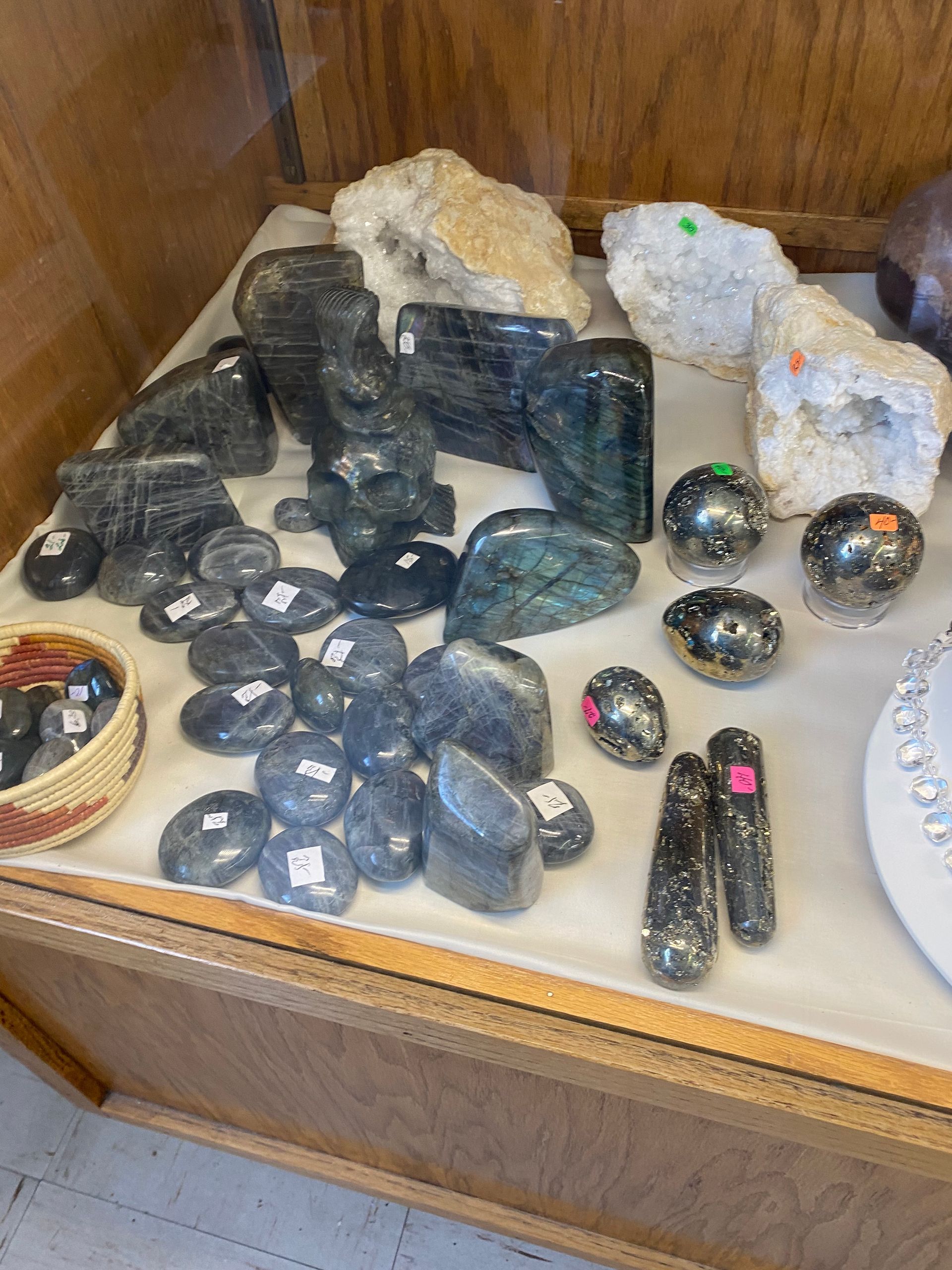 Assorted polished dark gemstones and crystal clusters displayed in a glass case.