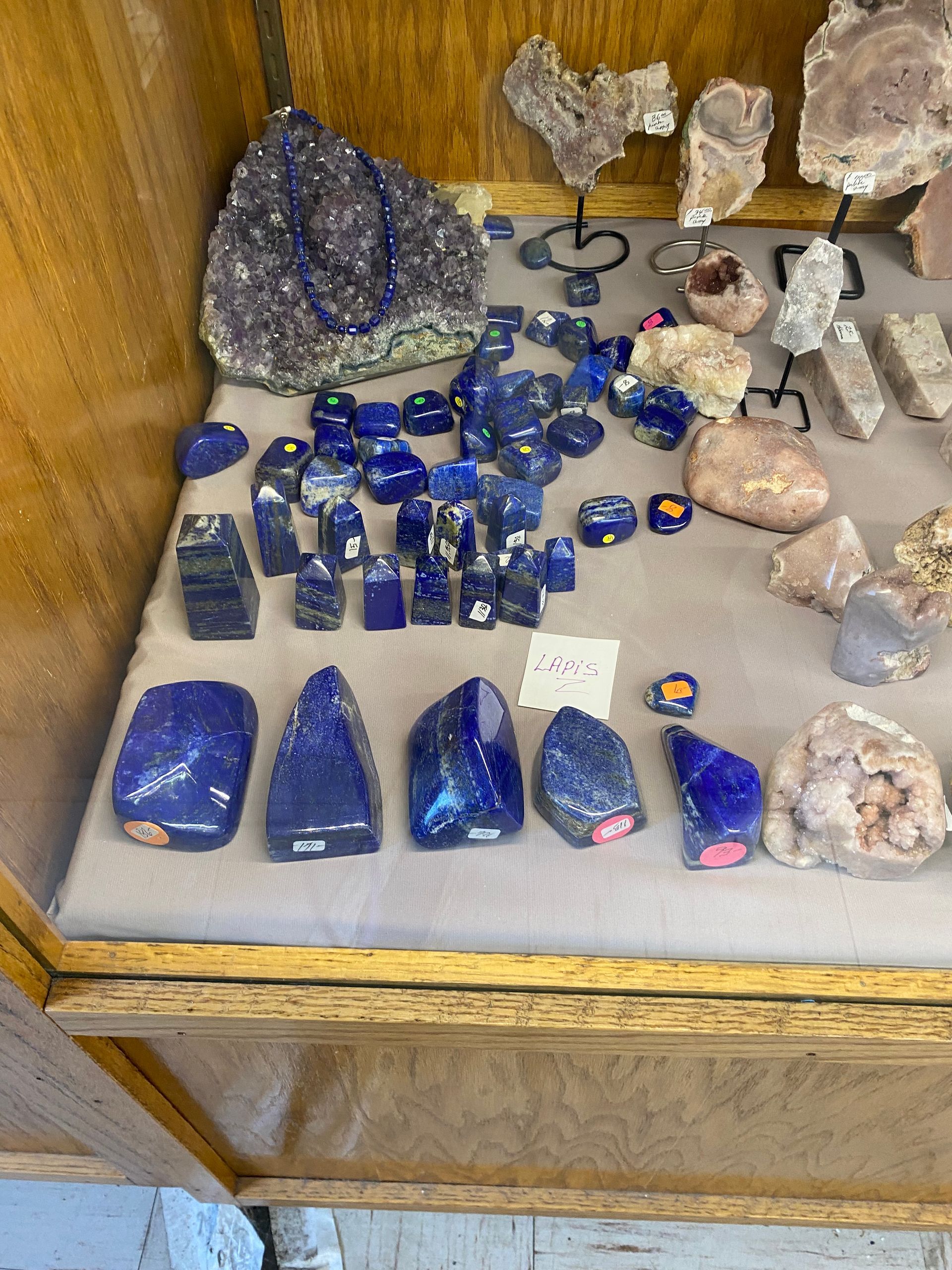 Display case of blue and clear crystals and polished stones on a shelf
