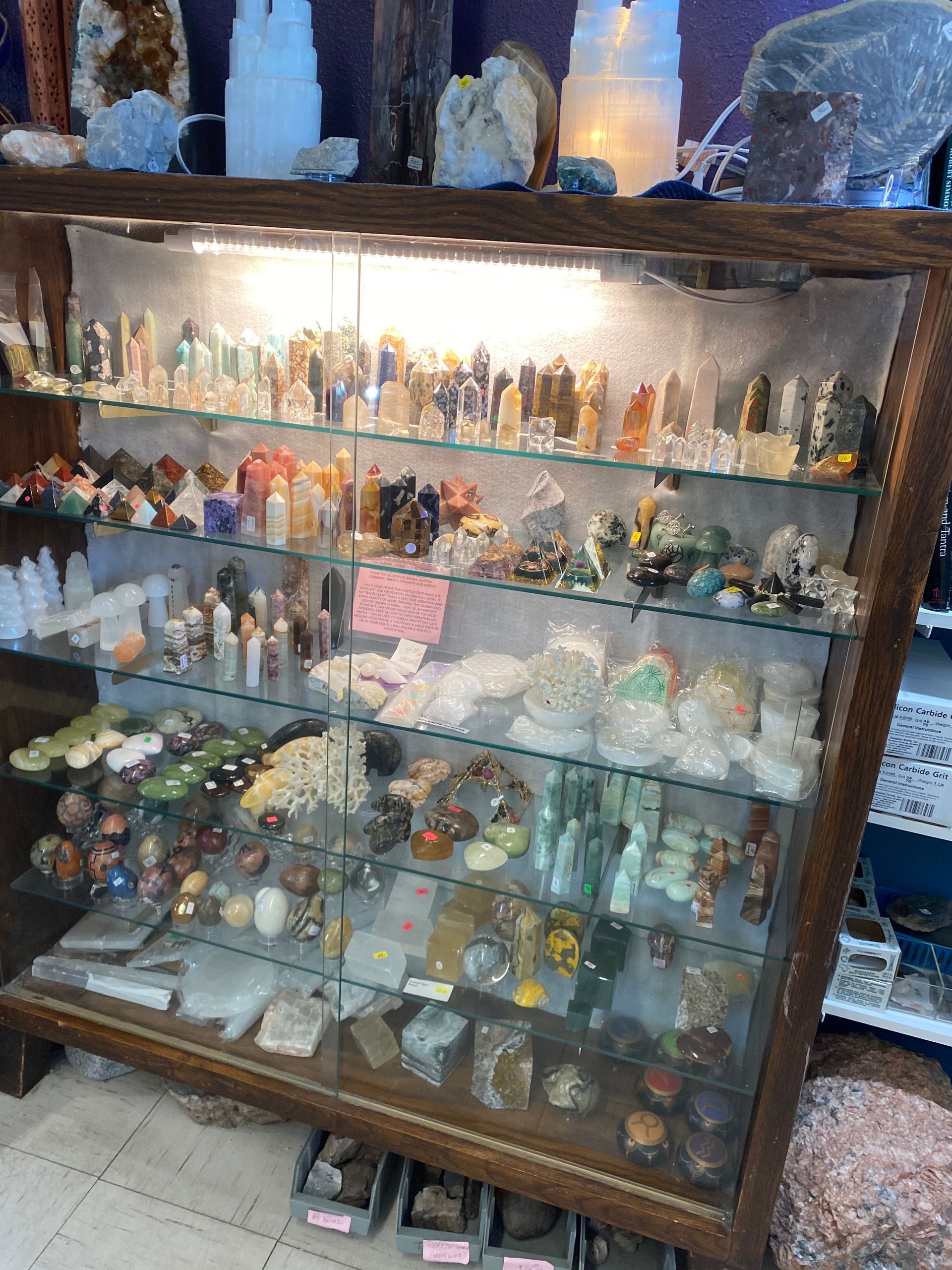 Glass display cabinet filled with crystals, figurines, and small stone carvings in a shop