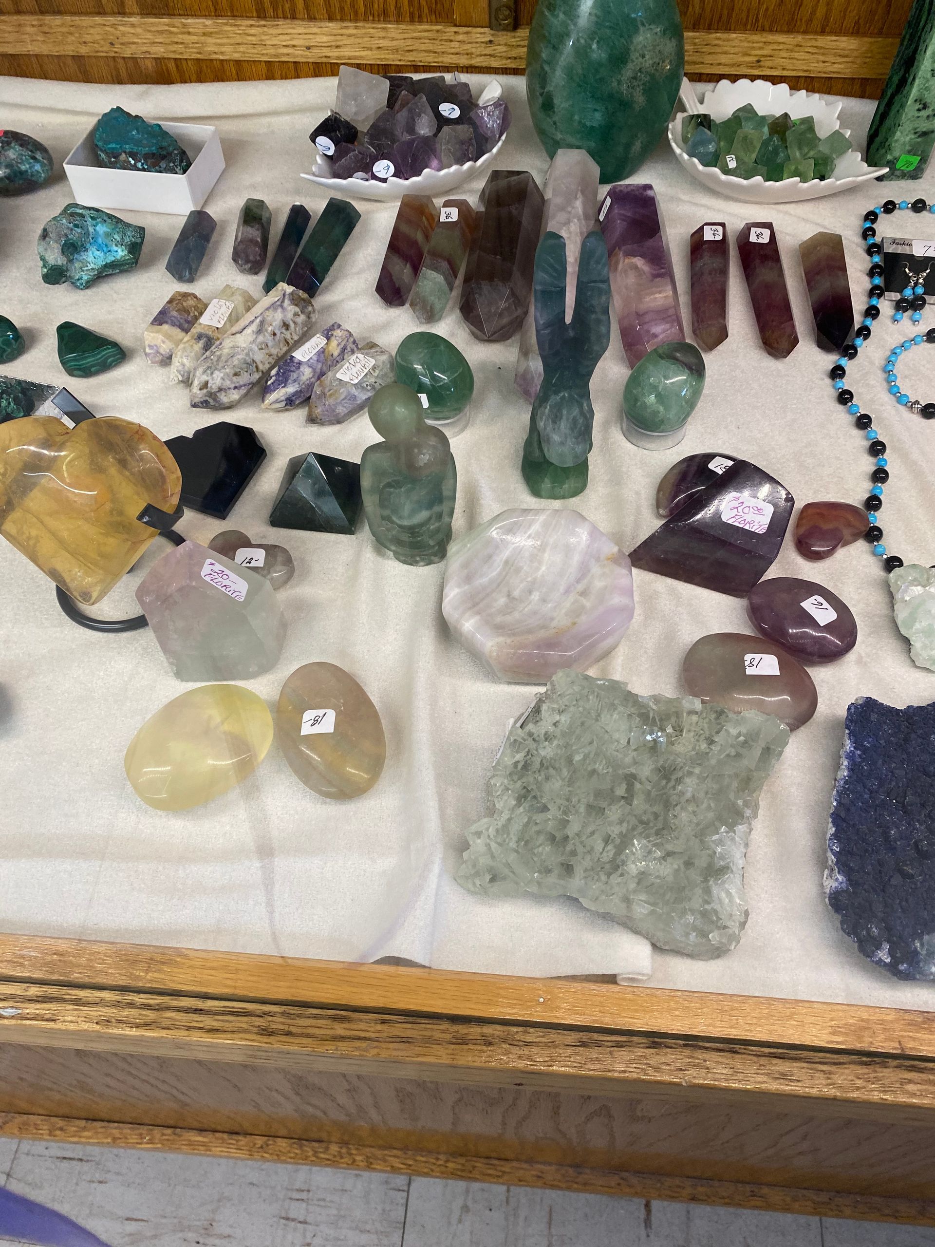 Assorted colorful crystals and gemstones arranged on a cloth-lined wooden display tray