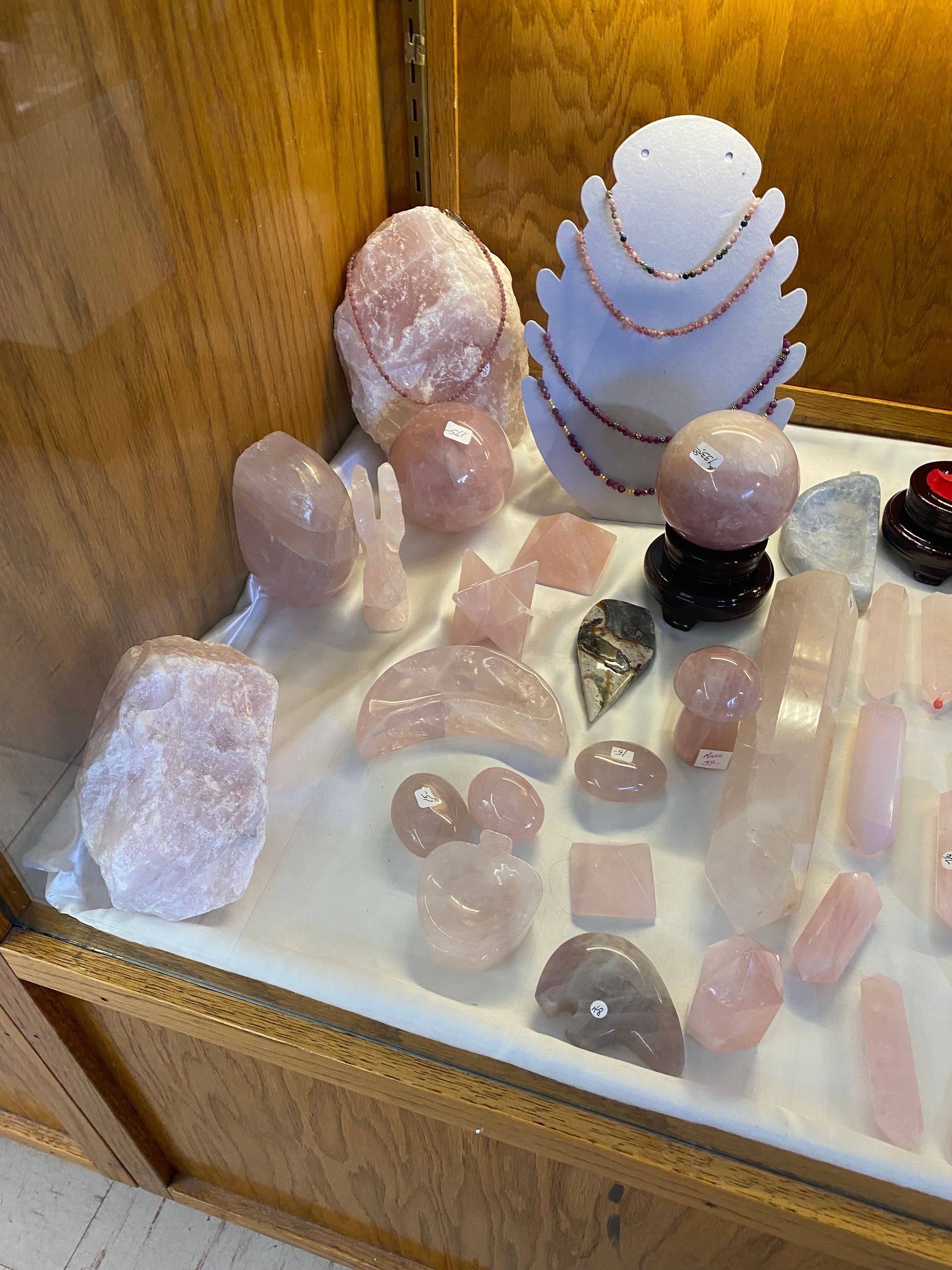Assorted pink and white crystal stones displayed on a wooden shelf.