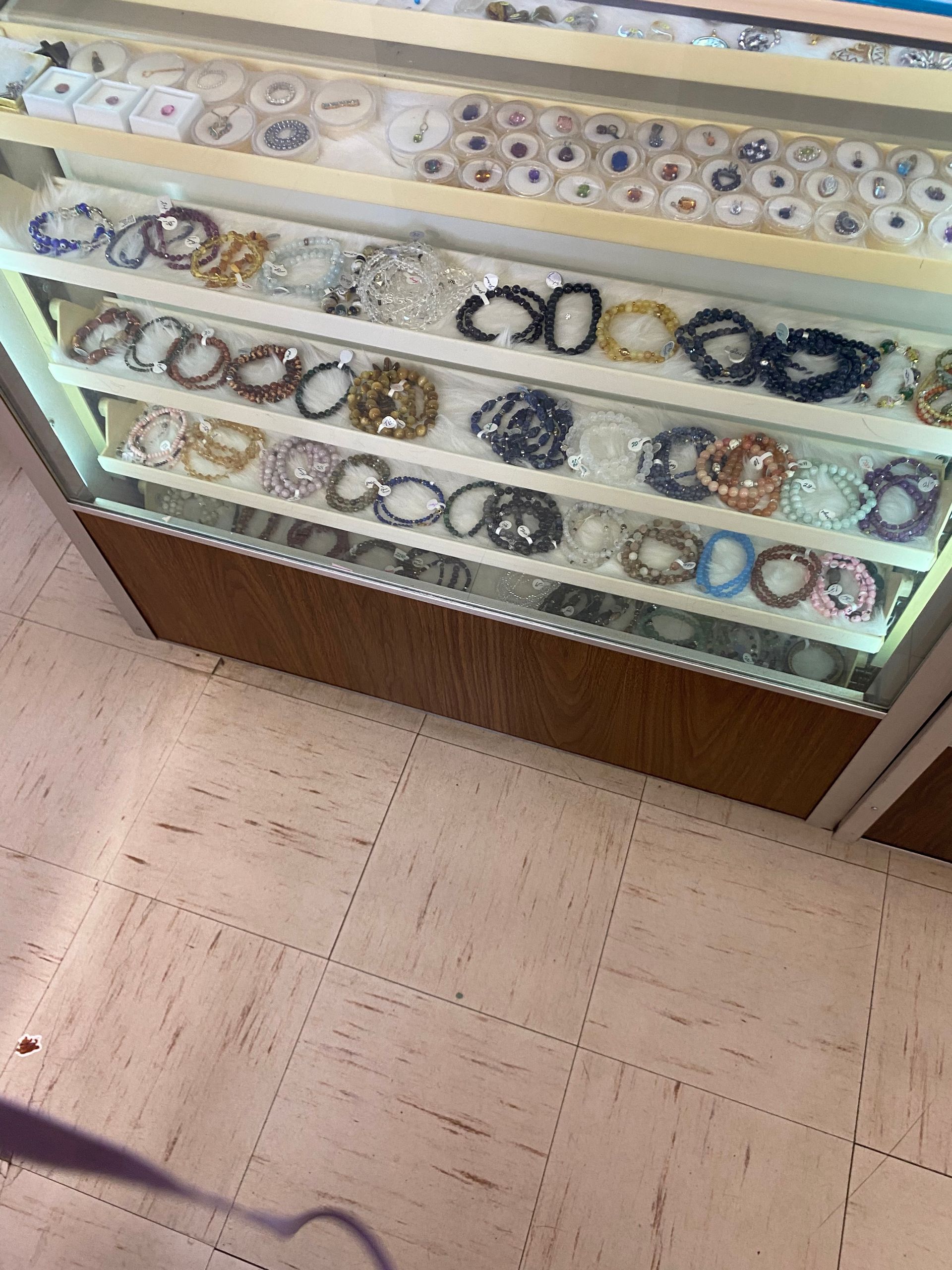 Glass display case filled with rows of colorful bracelets and bangles in a jewelry store.