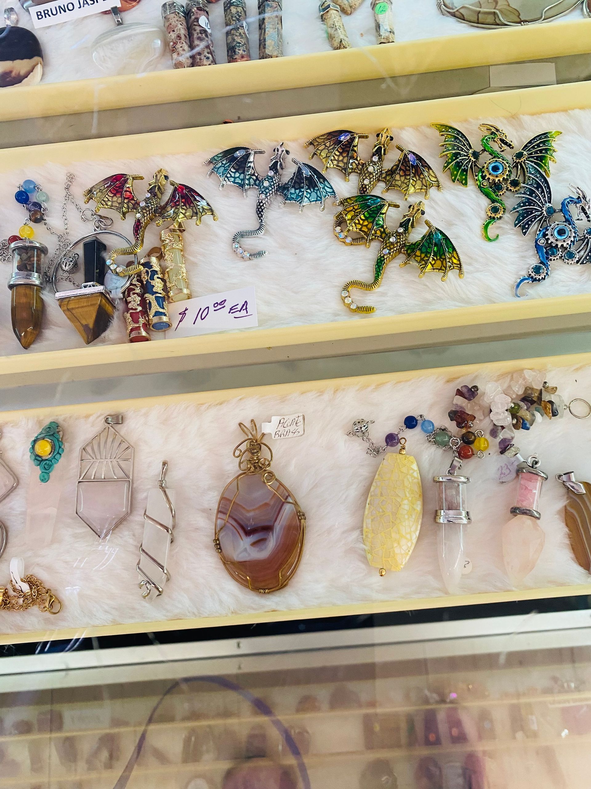Display of colorful handmade beaded pendants and jewelry on trays in a craft market booth