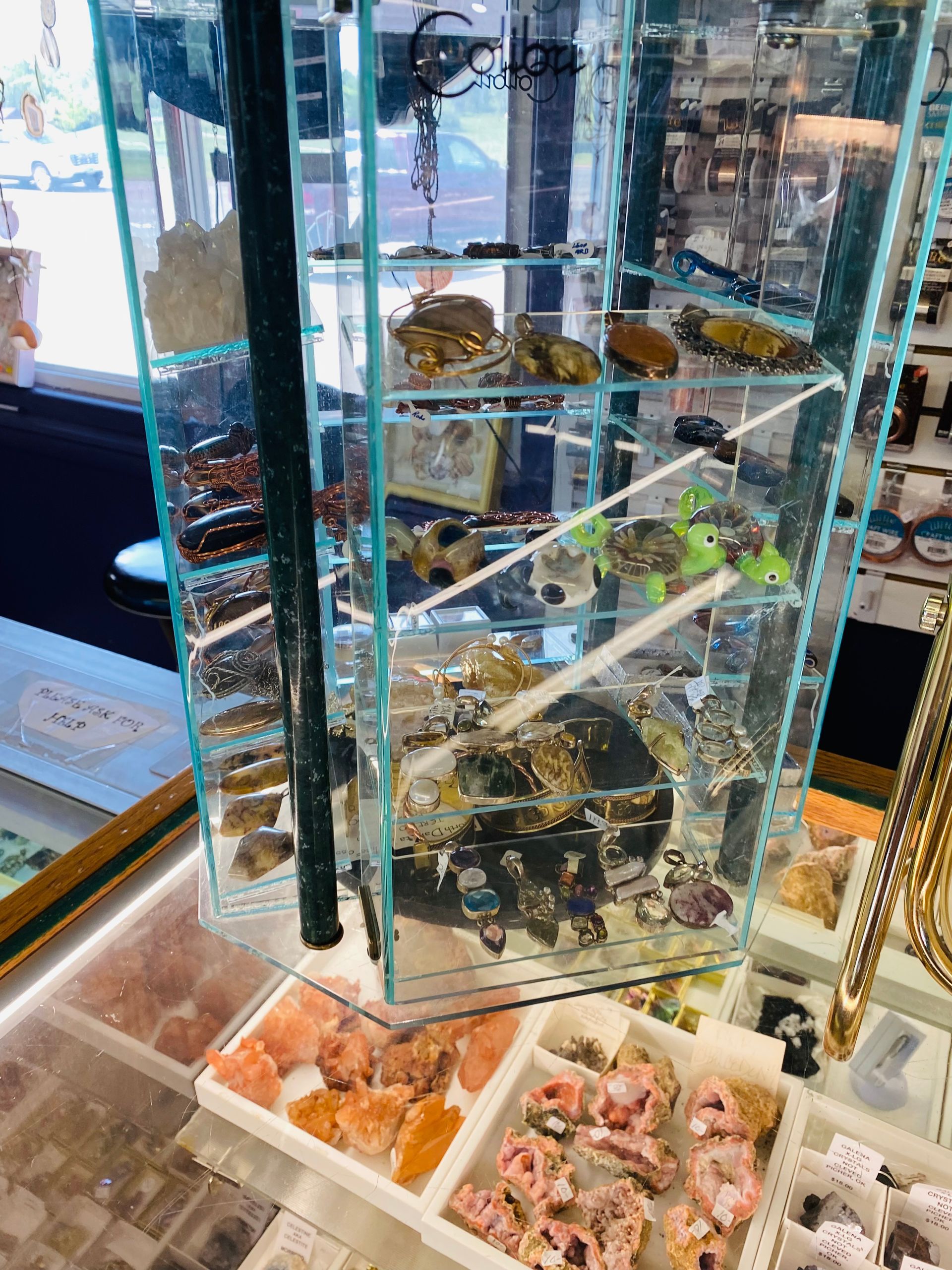 Assorted sea glass and small shell-filled decorative boxes on a glass store display shelf