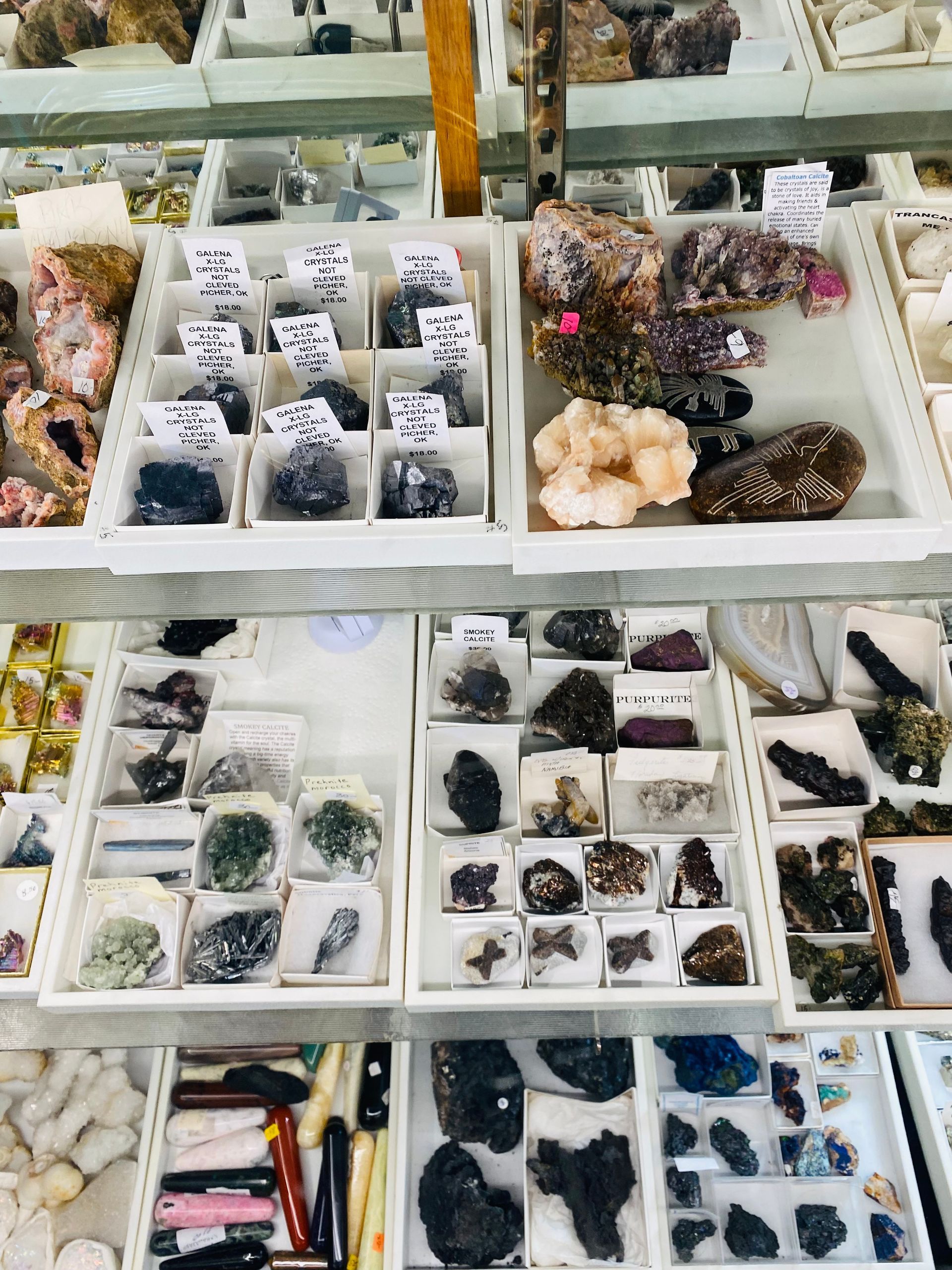 Assorted mineral and crystal specimens arranged in trays at a market stall