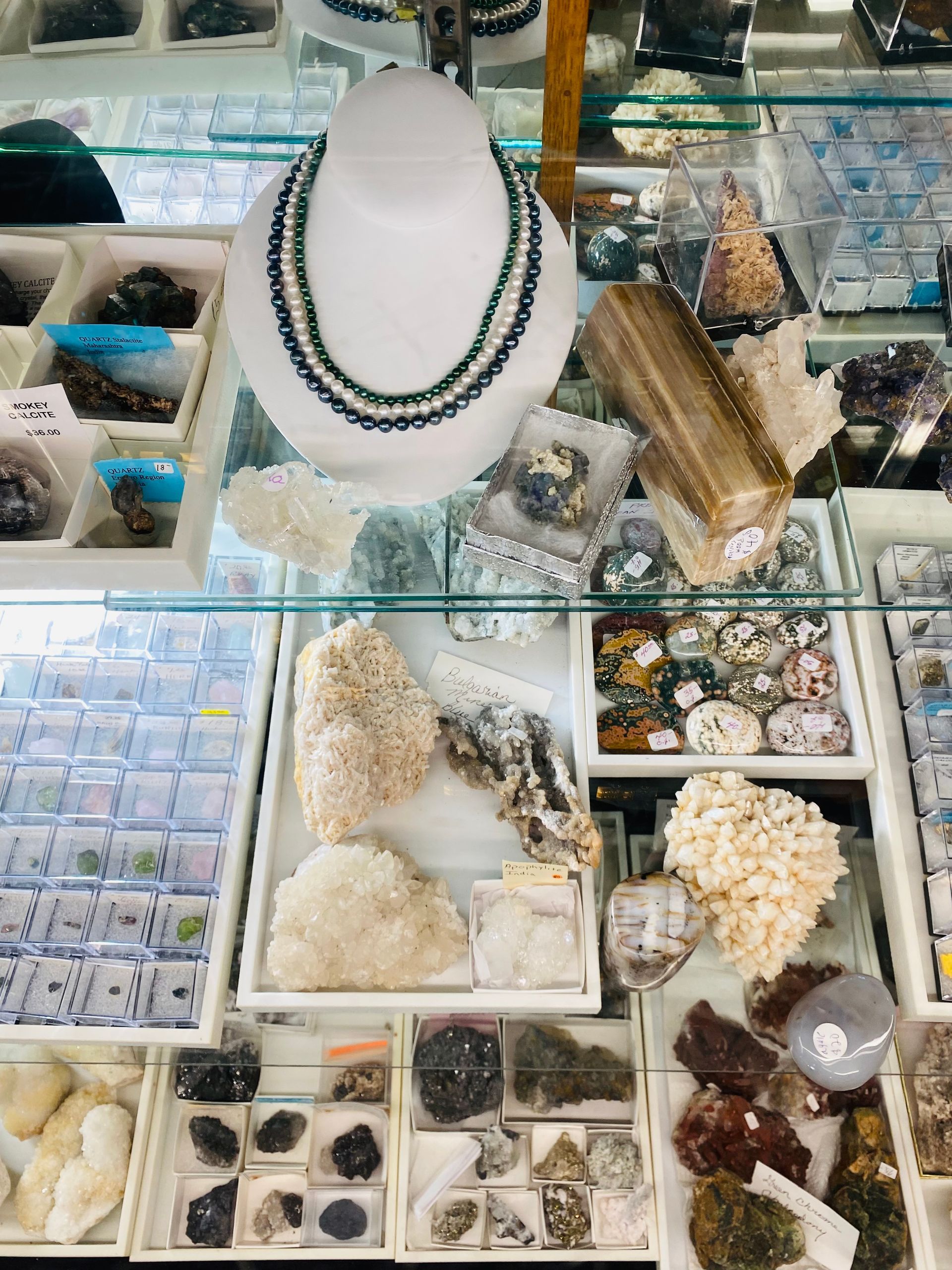Jewelry and crystal display case with necklaces, mineral specimens, and small stone collections