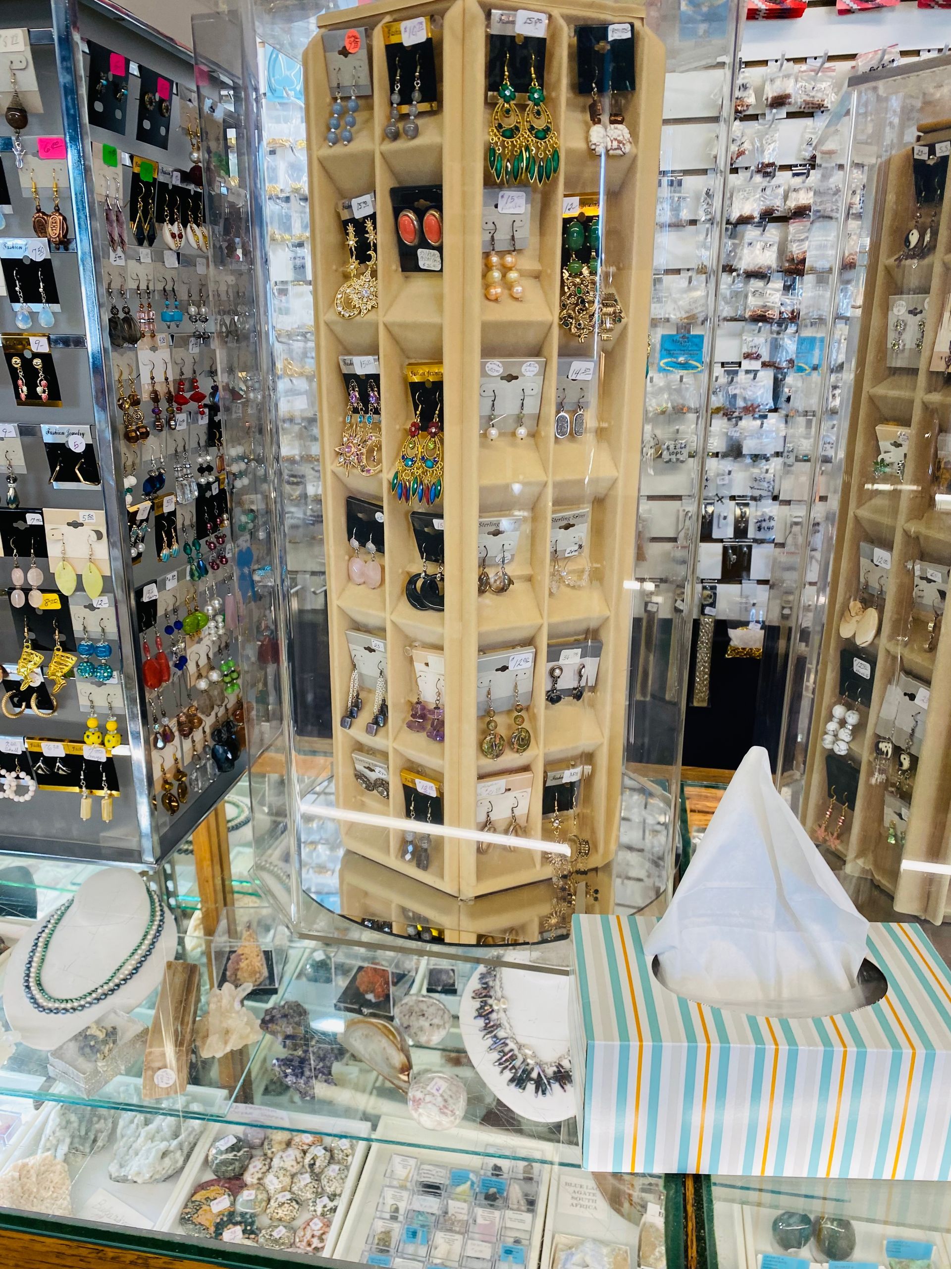 Jewelry display with necklaces, bracelets, and earrings on wooden stands in a shop counter