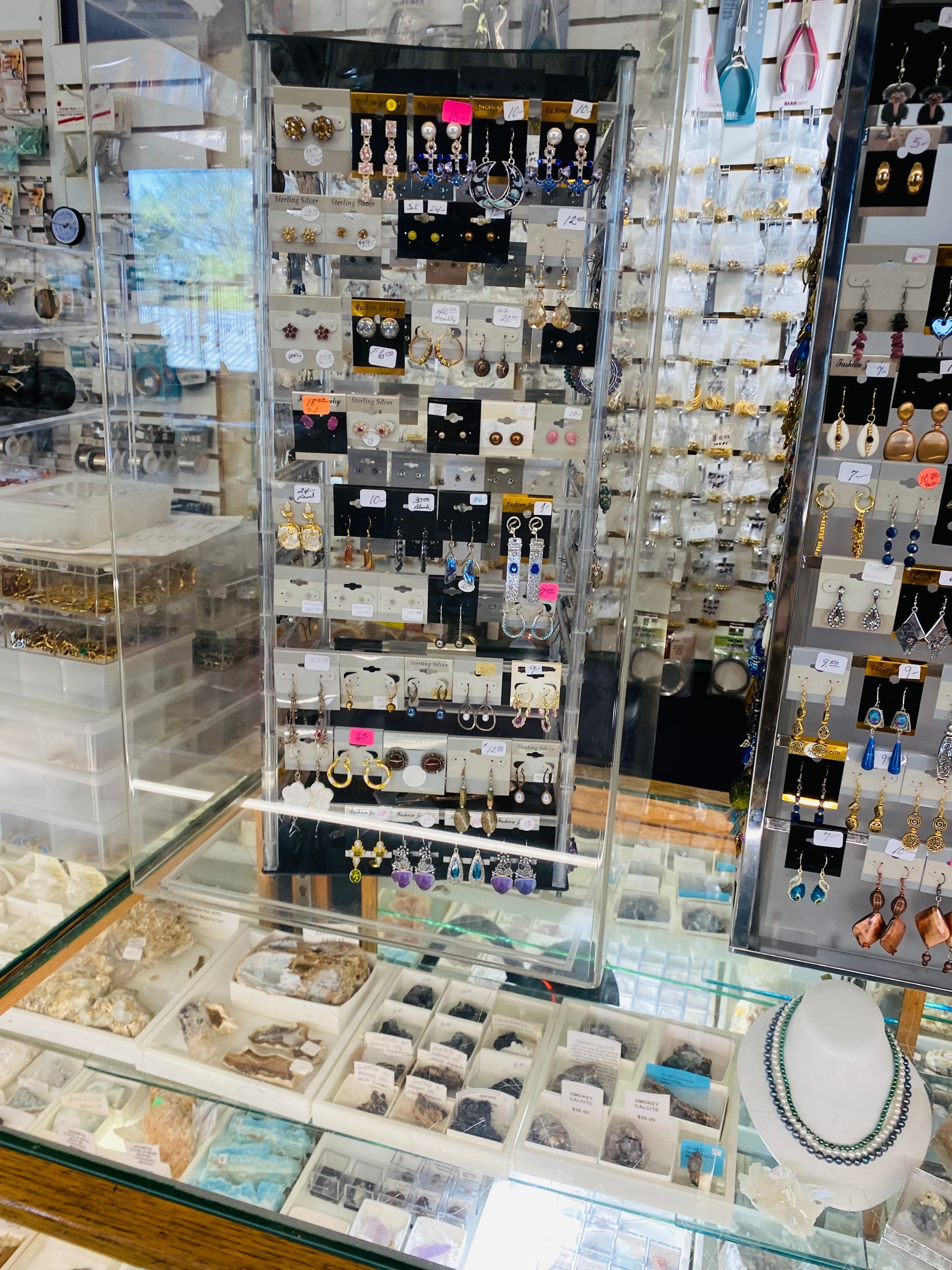 Jewelry store display cases filled with earrings, necklaces, and bracelets on white shelves