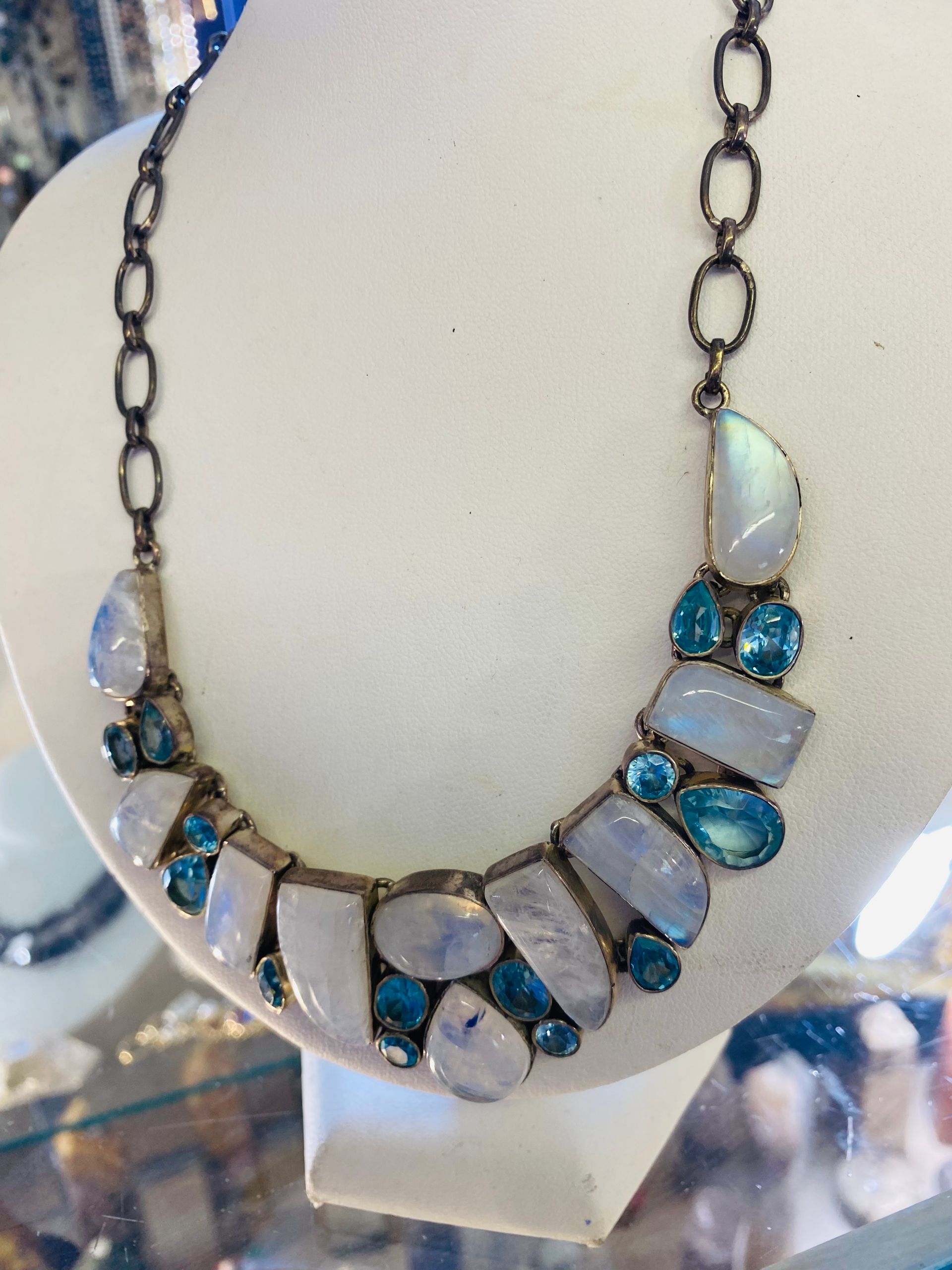 Opal and blue gemstone necklace with silver chain on a display bust
