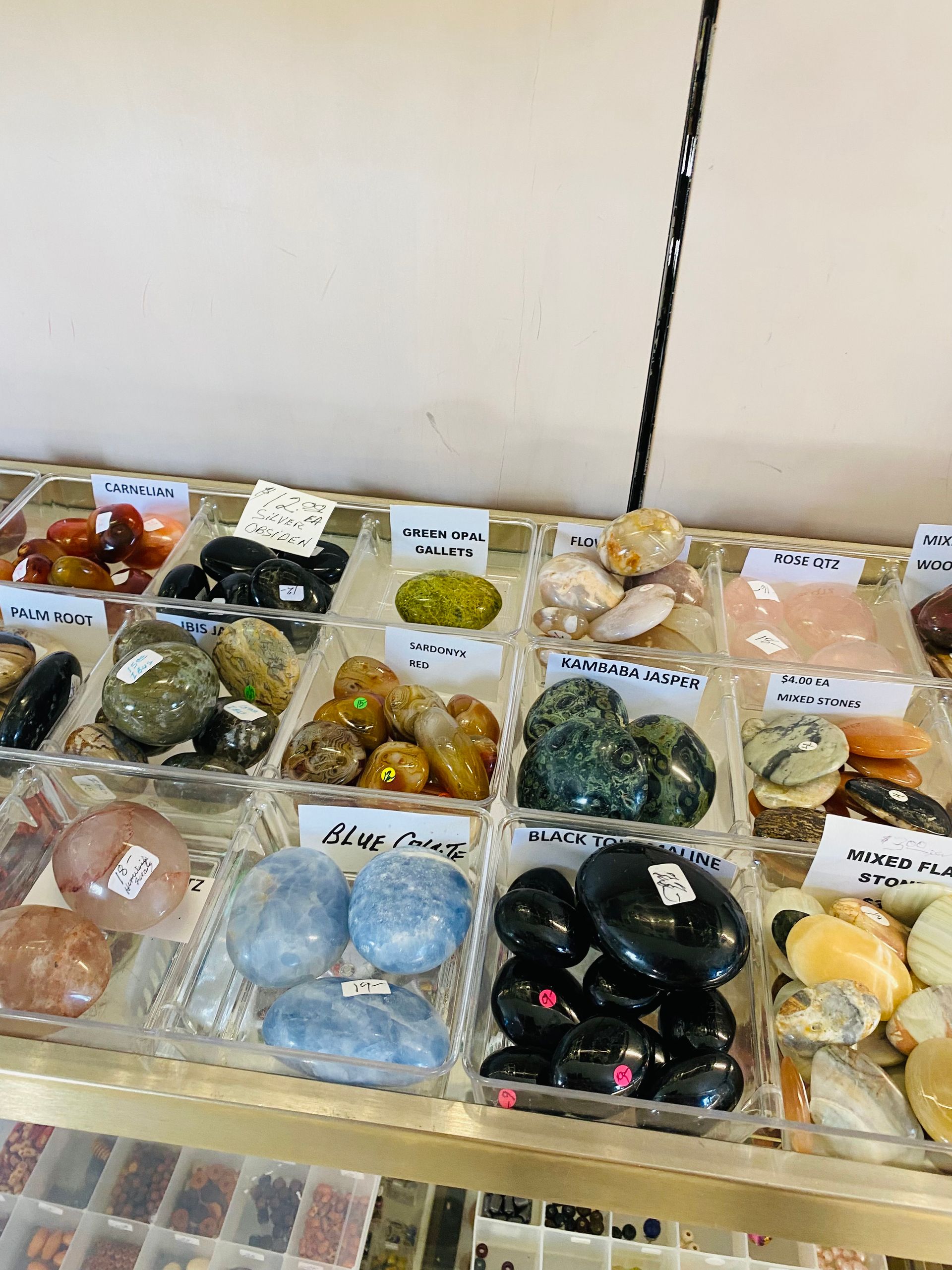 Assorted polished stones and crystals displayed in labeled trays on a table.