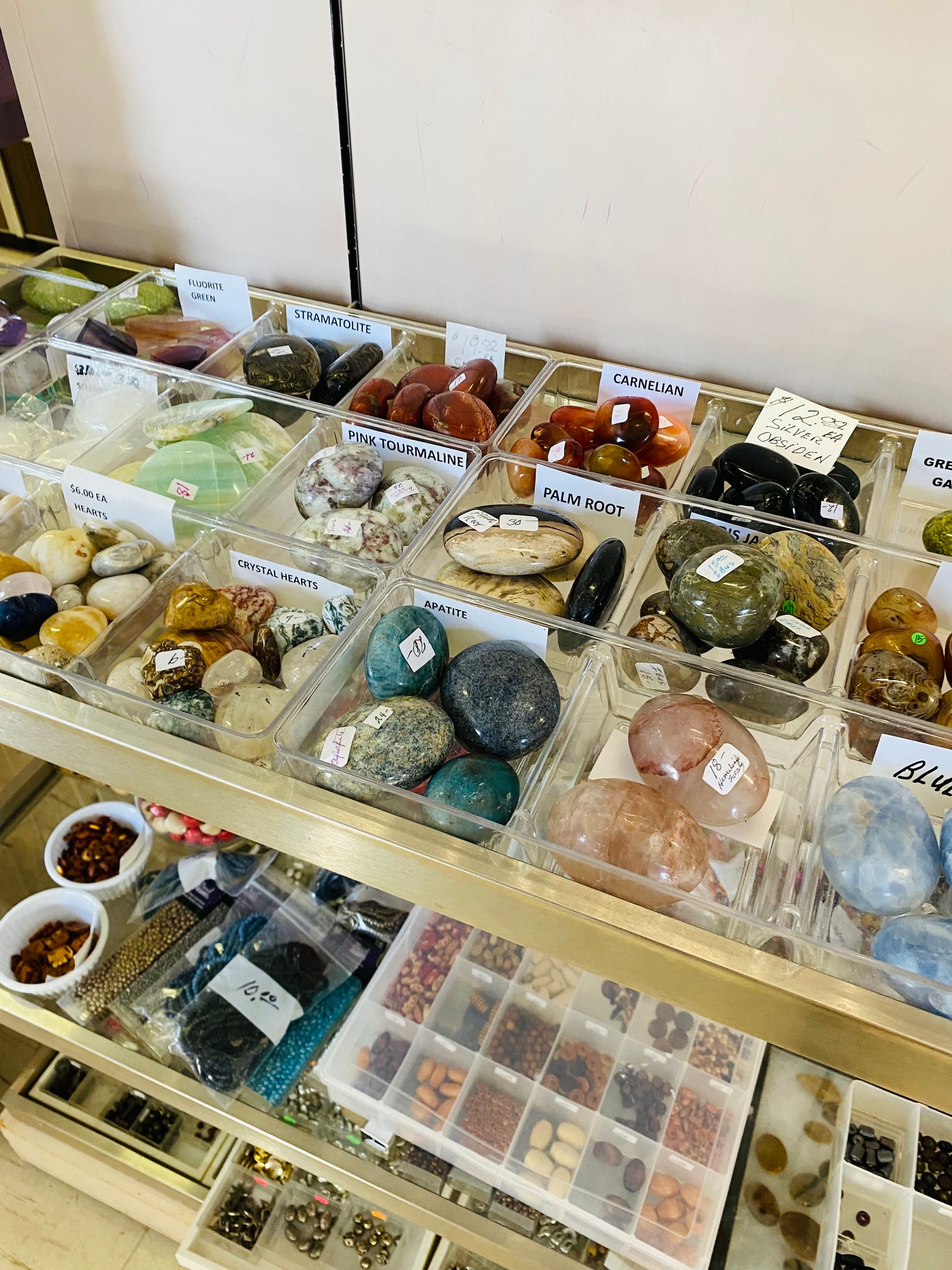Display of assorted gemstone and crystal items arranged in trays on a shop counter.