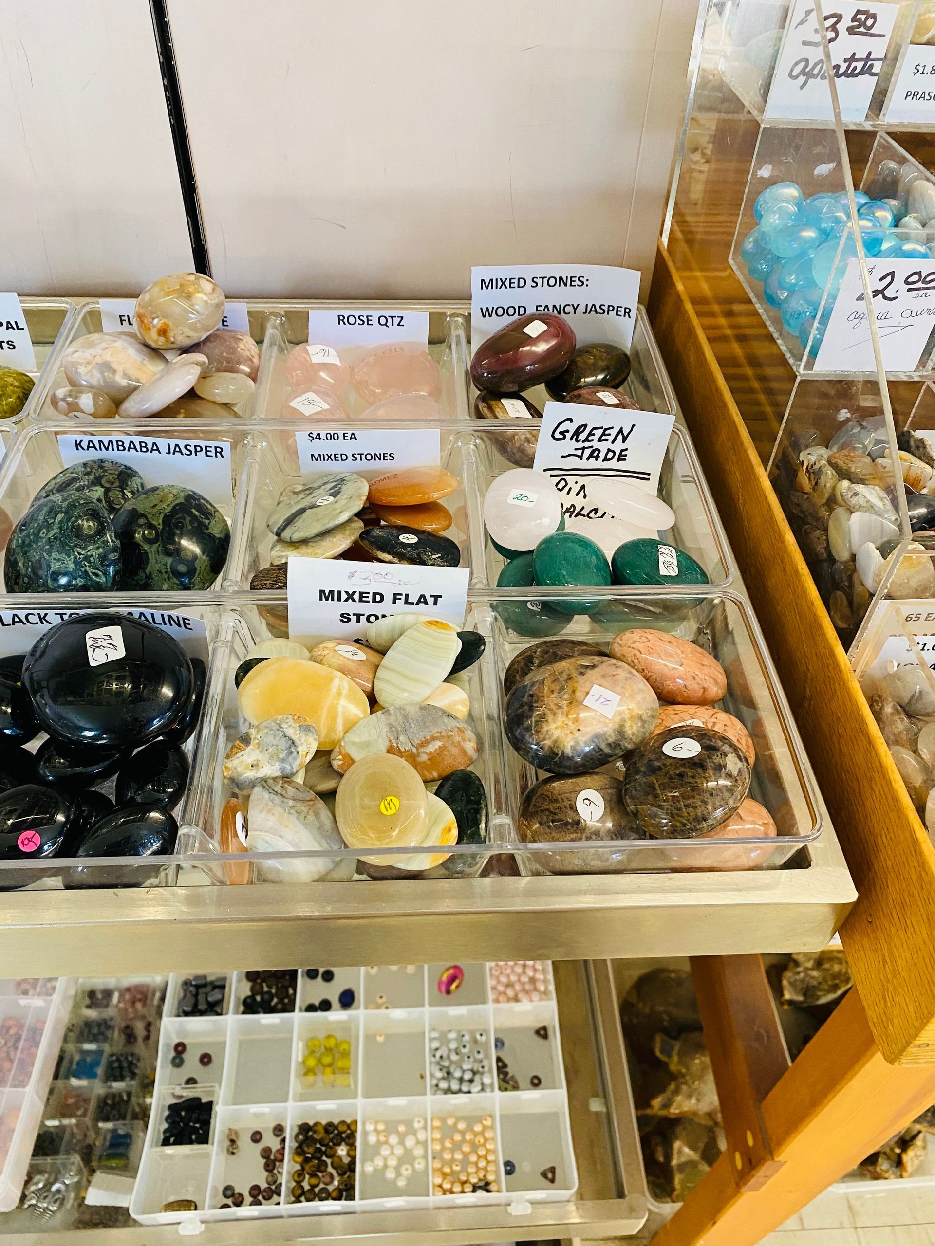 Display of assorted crystal and gemstone spheres in trays and boxes inside a shop display case