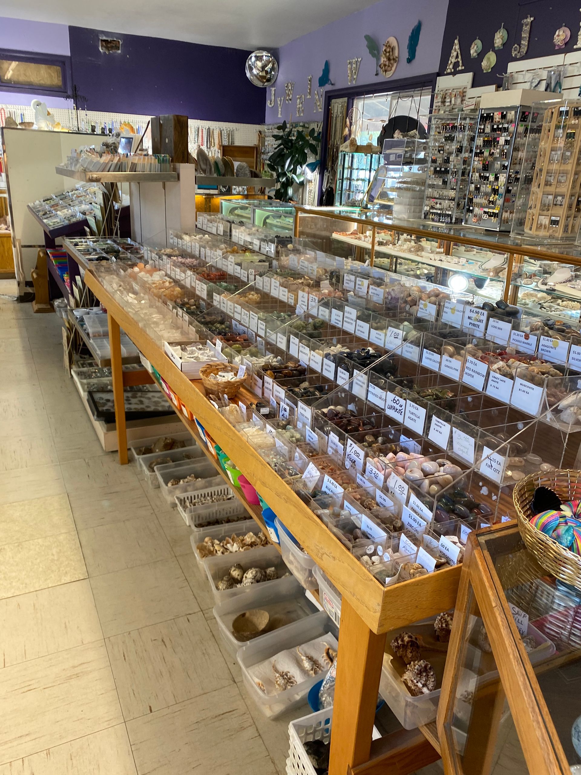 Candy shop aisle with rows of bulk sweets in clear bins and shelves of treats along the wall