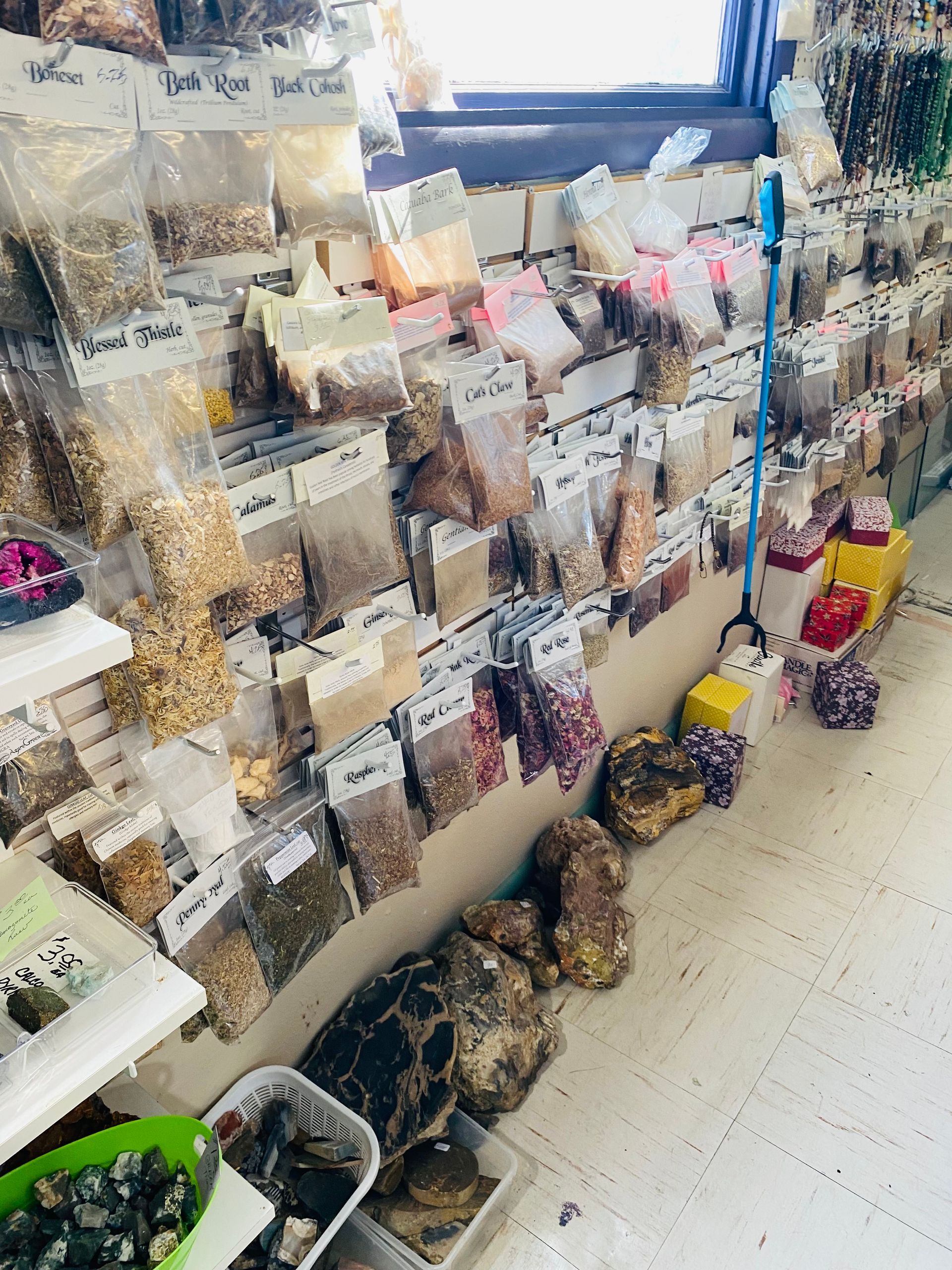 Display of packaged craft supplies and gift items in a store aisle, with bins on the floor and shelves by a window