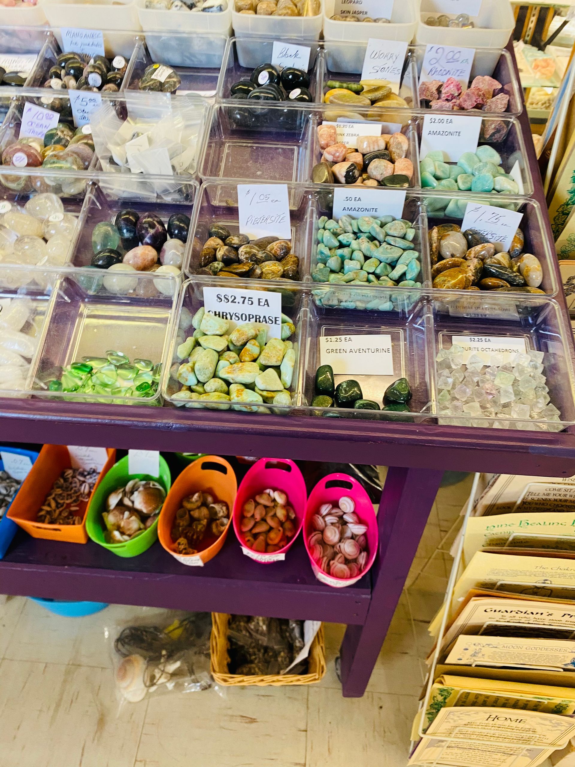 Assorted candies and snacks displayed in bins on a purple market table.
