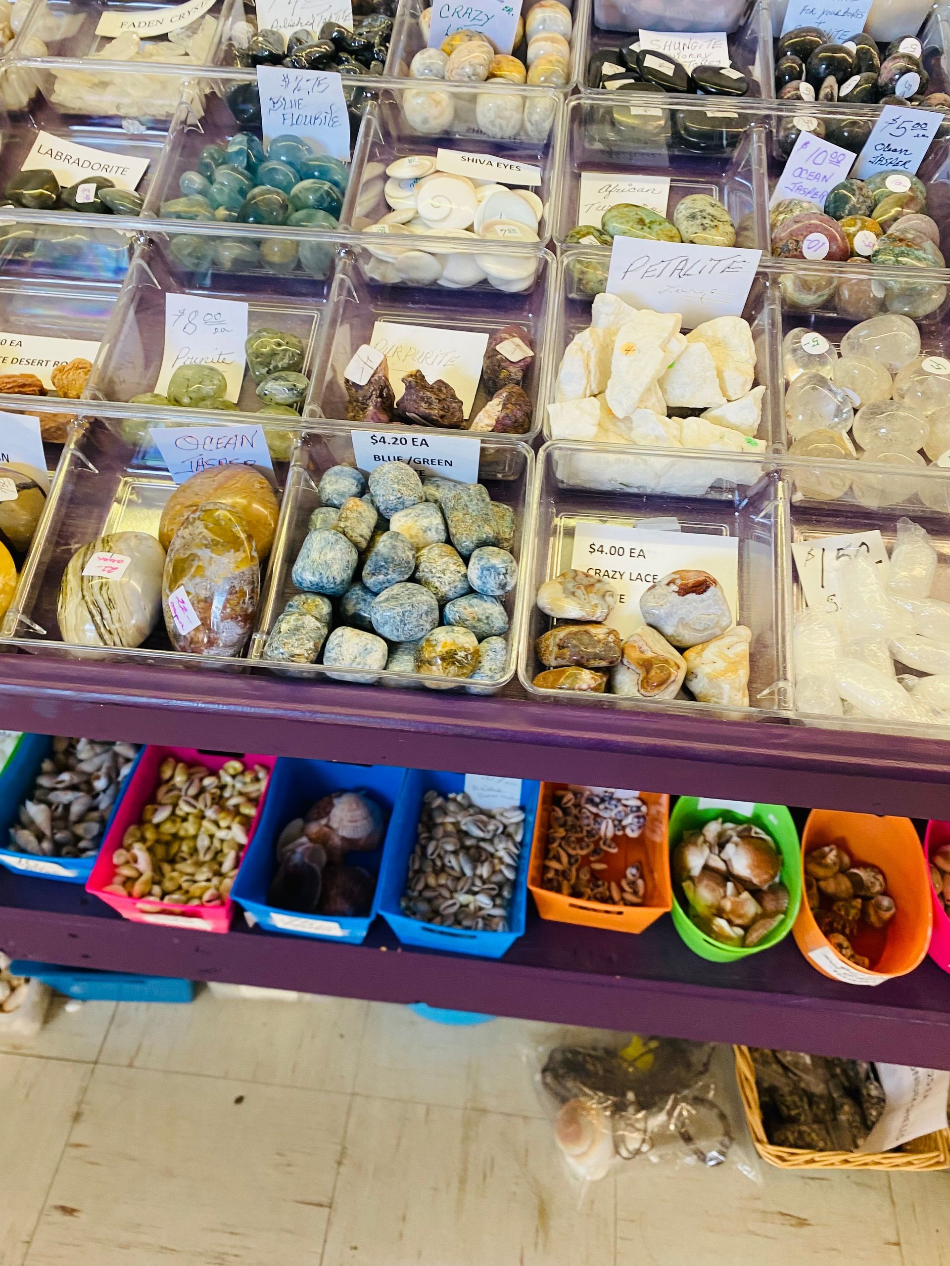 Street market stall with trays of assorted sweets and colorful snacks in plastic containers