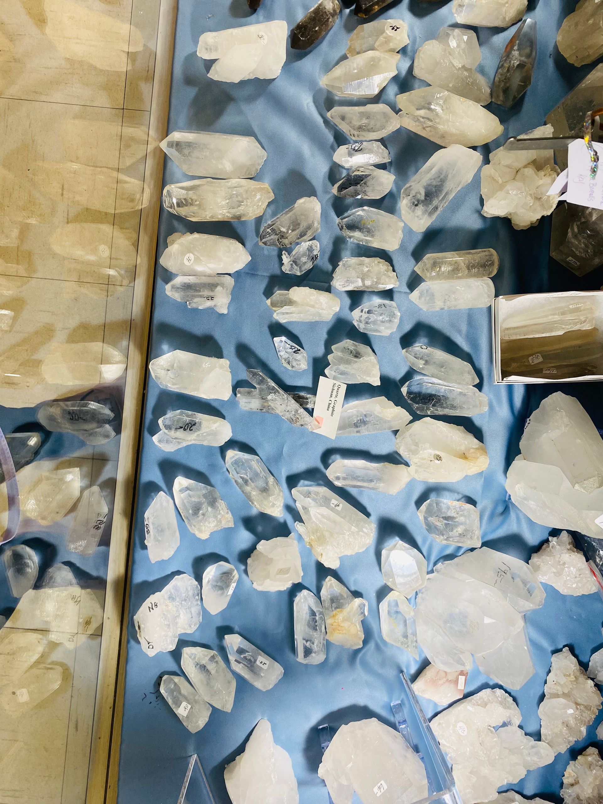 Top-down view of pale rocks or shells arranged on blue fabric, with a beige textured strip on the left.