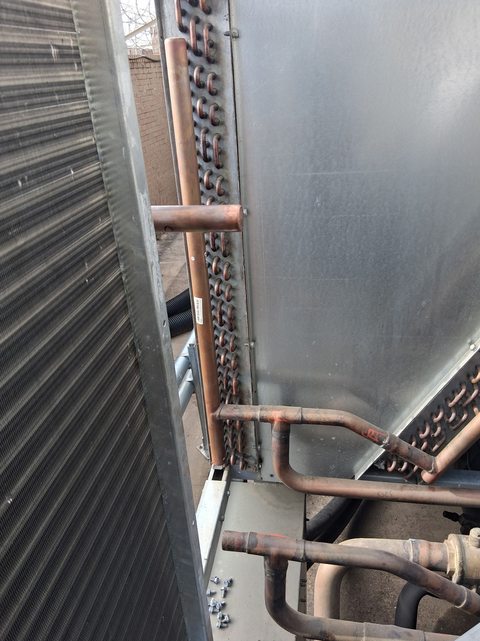 Narrow industrial walkway with rusted pipes and metal walls beside a large textured panel