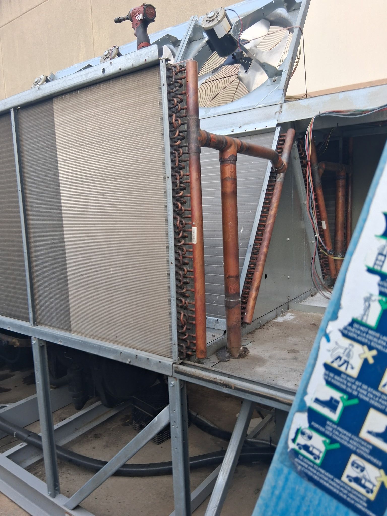 Damaged rooftop HVAC unit with bent metal framing and broken panels on a raised platform