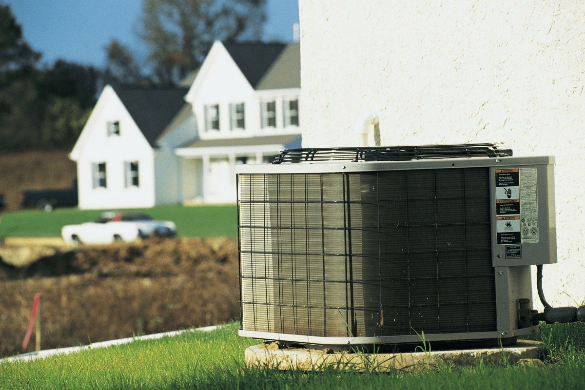 An air conditioner is sitting on the side of a house.