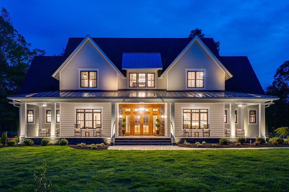 A large white house with a porch is lit up at night.