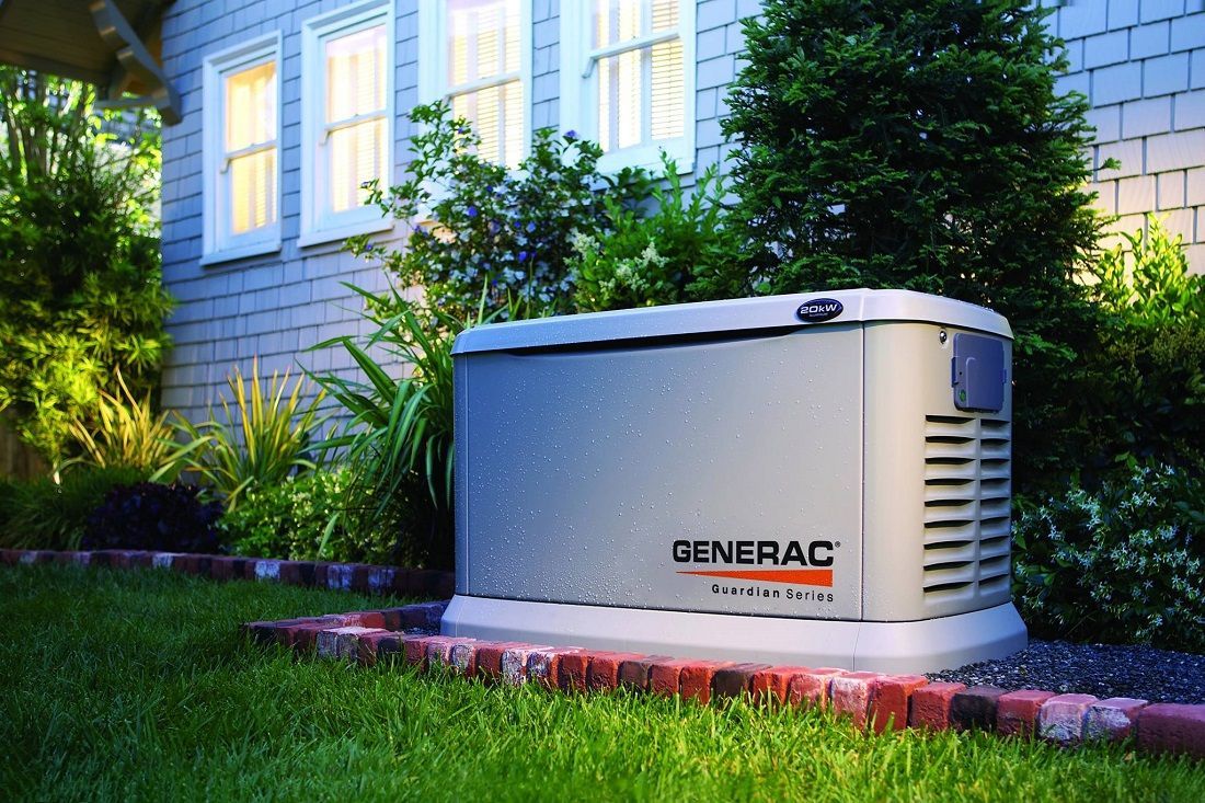 A generator is sitting in the grass in front of a house.
