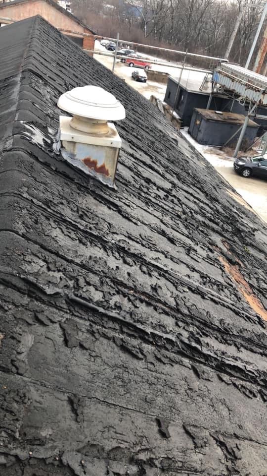 Rooftop with a black shingle surface and a white vent pipe near the ridge, seen from above