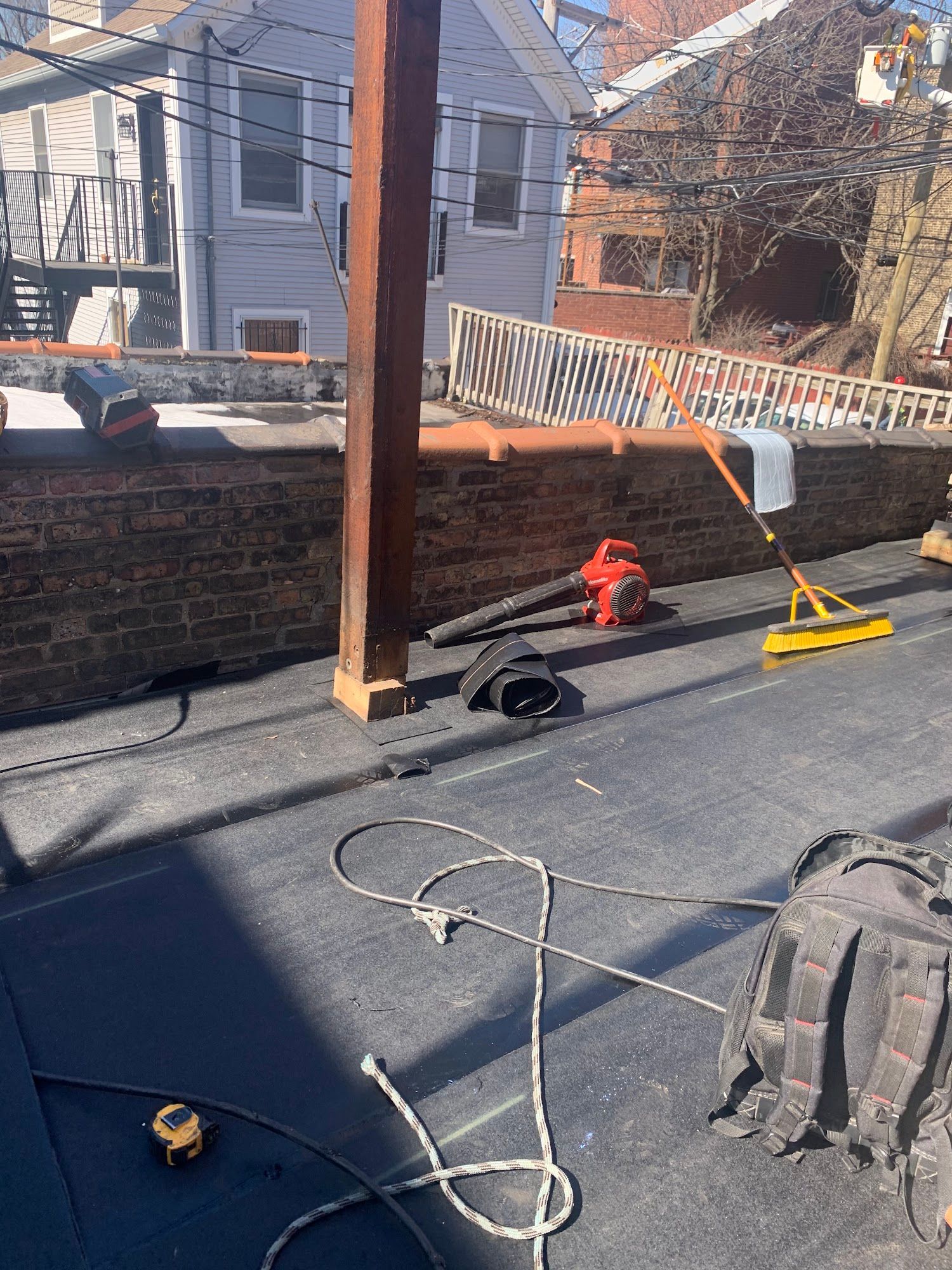 Rooftop repair scene with brick wall, broom, fire hydrant, and scattered tools on a flat roof