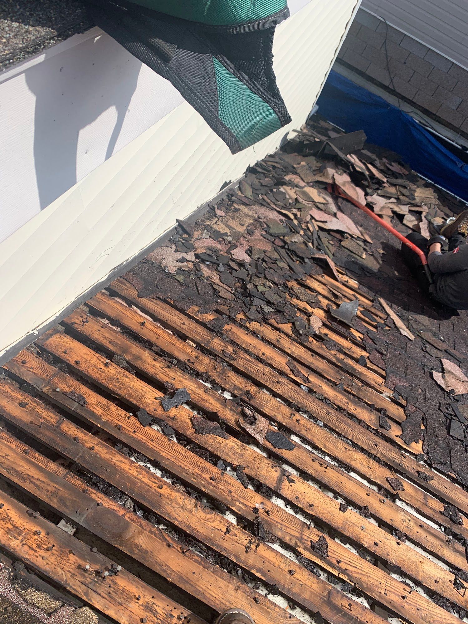 Charred roof decking with exposed wooden slats and debris near a damaged wall
