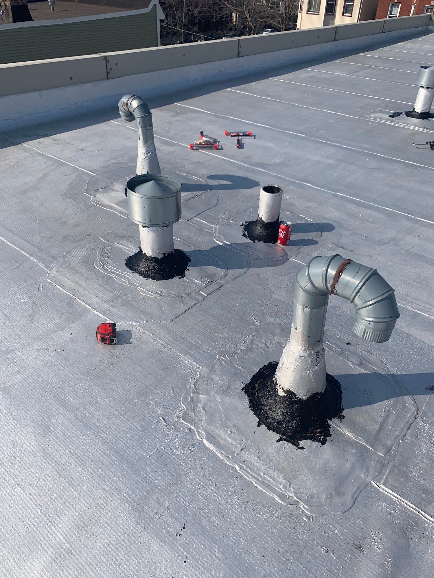 Rooftop with HVAC vents, pipes, and ductwork on a flat gray roof.
