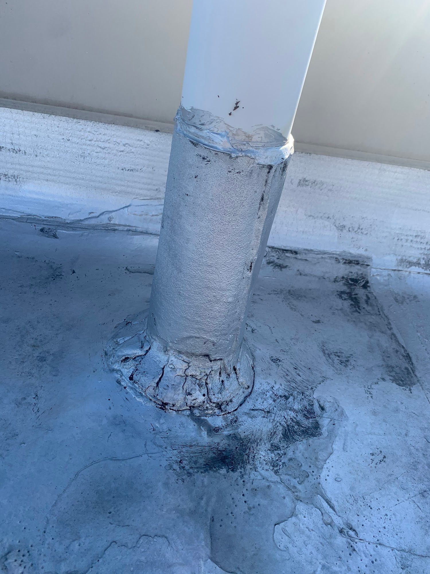 White metal post with peeling paint and rust stains on a weathered concrete surface
