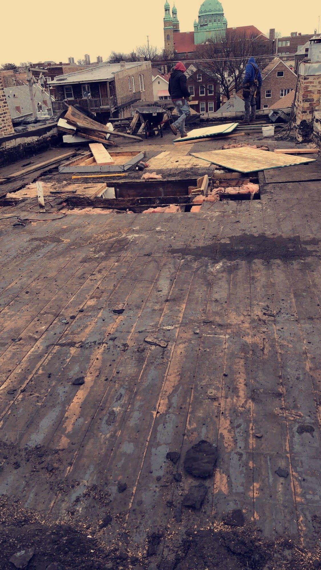 Rooftop aftermath with scattered debris and a distant skyline under a cloudy sky