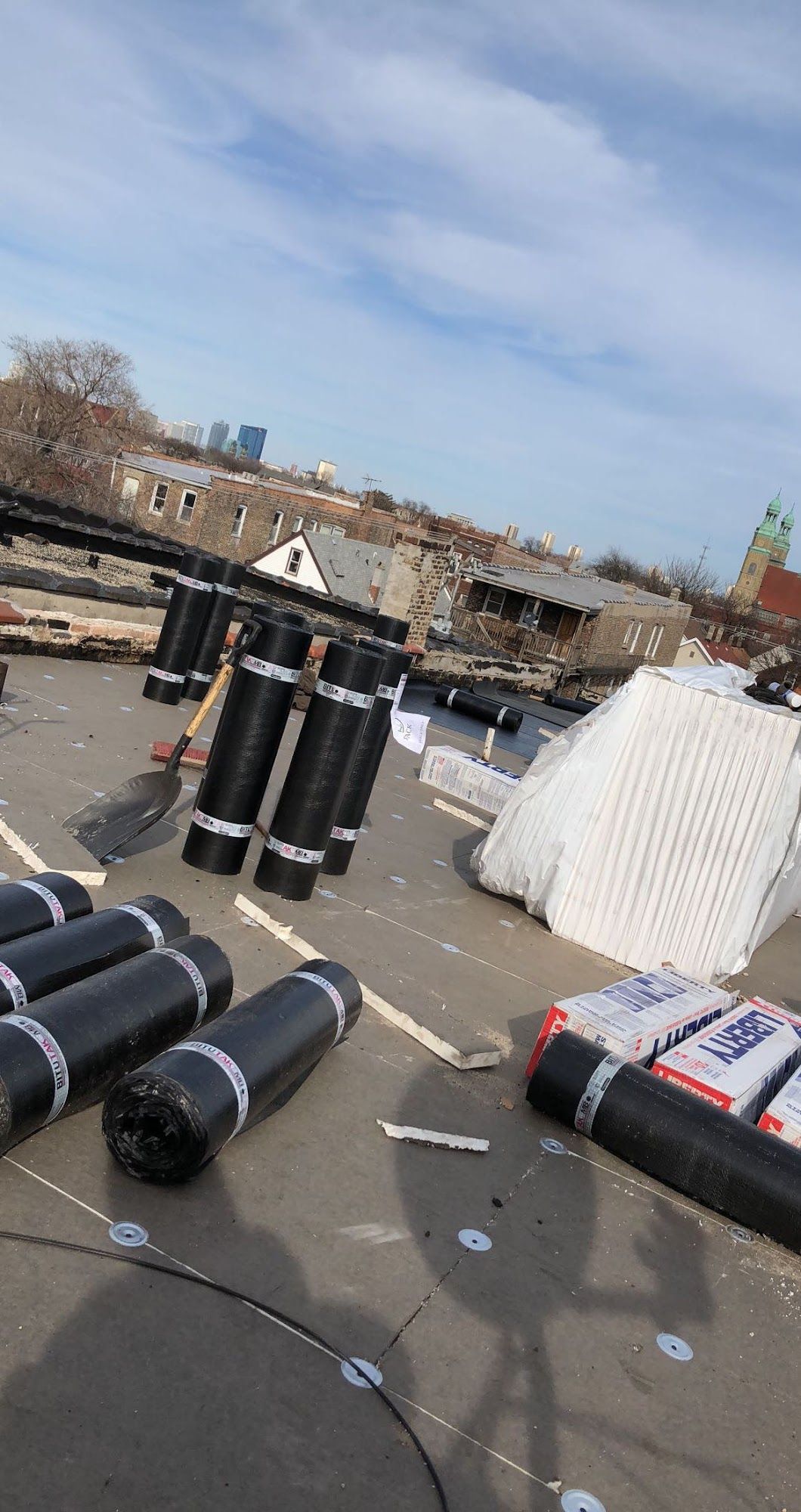 Scattered black and white cylindrical rolls on pavement near a waterfront under a blue sky