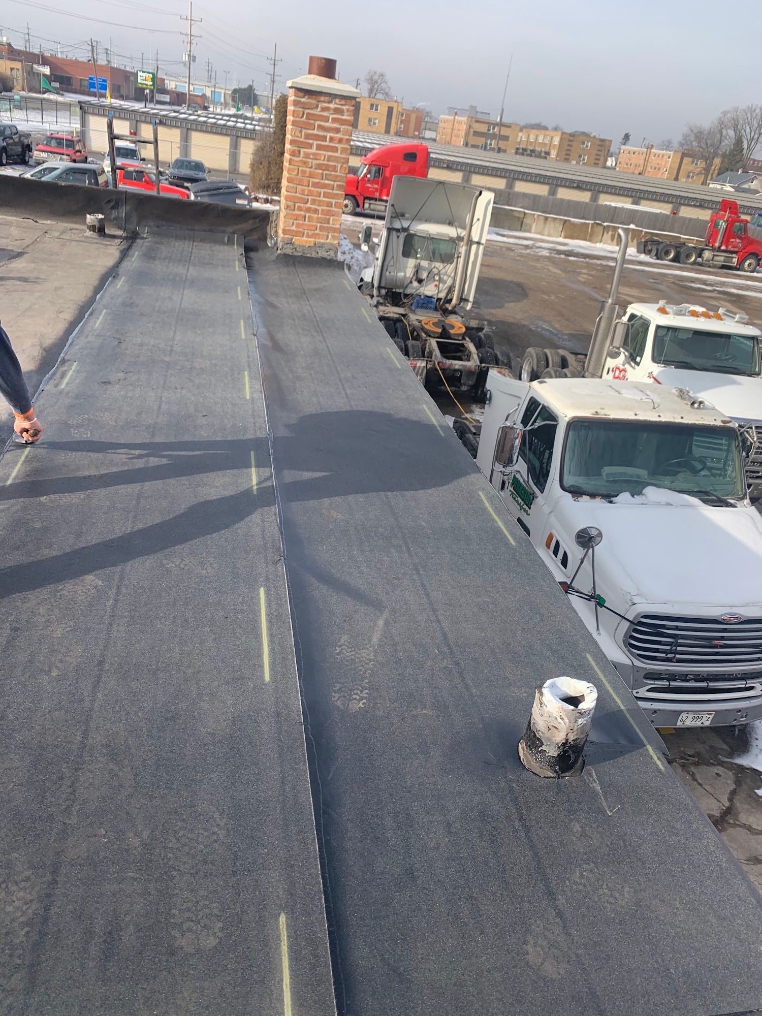Rooftop with workers, a white truck, and a city skyline in the background.