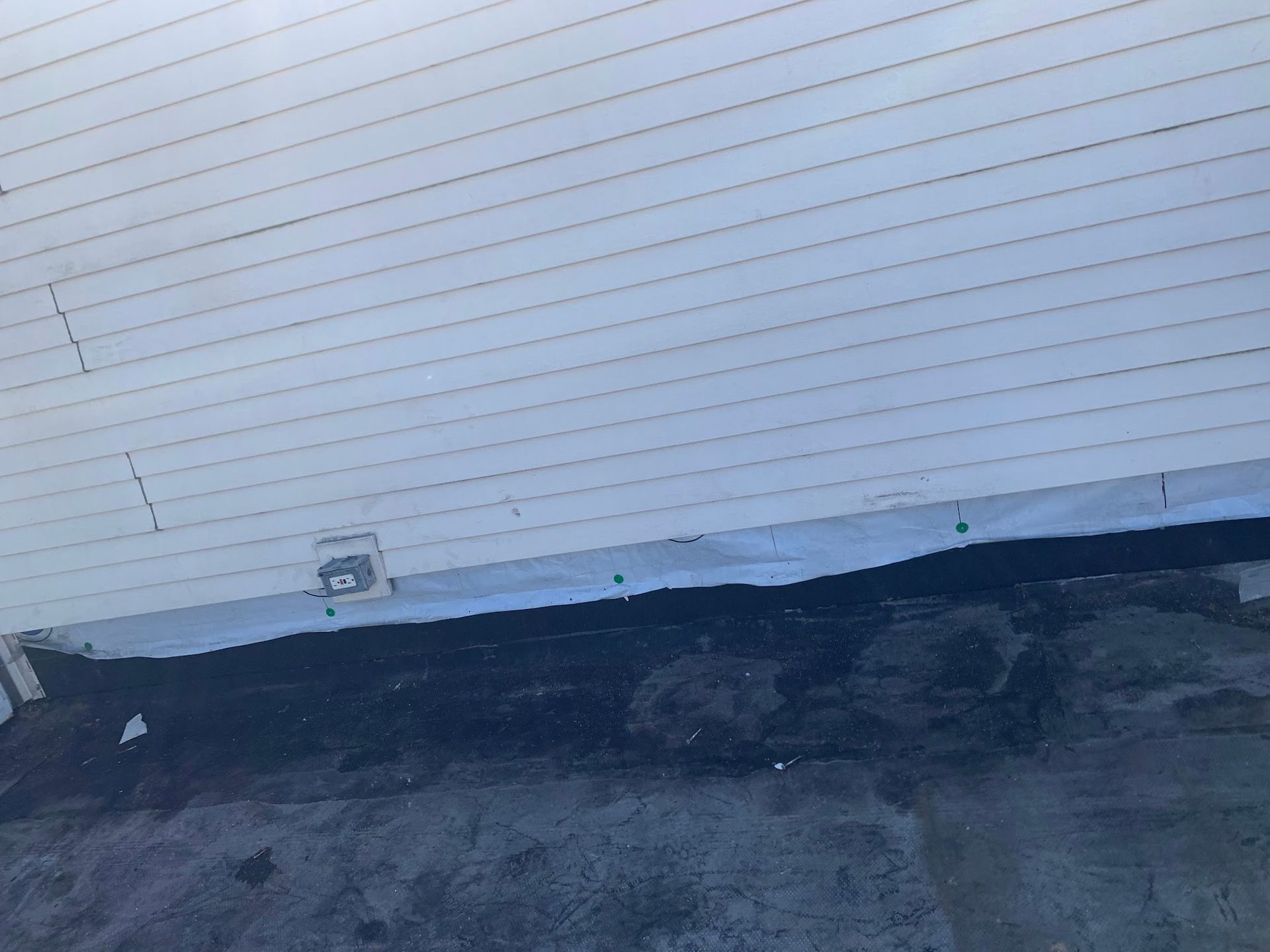 White garage door above dark pavement, with a small utility box near the bottom left.