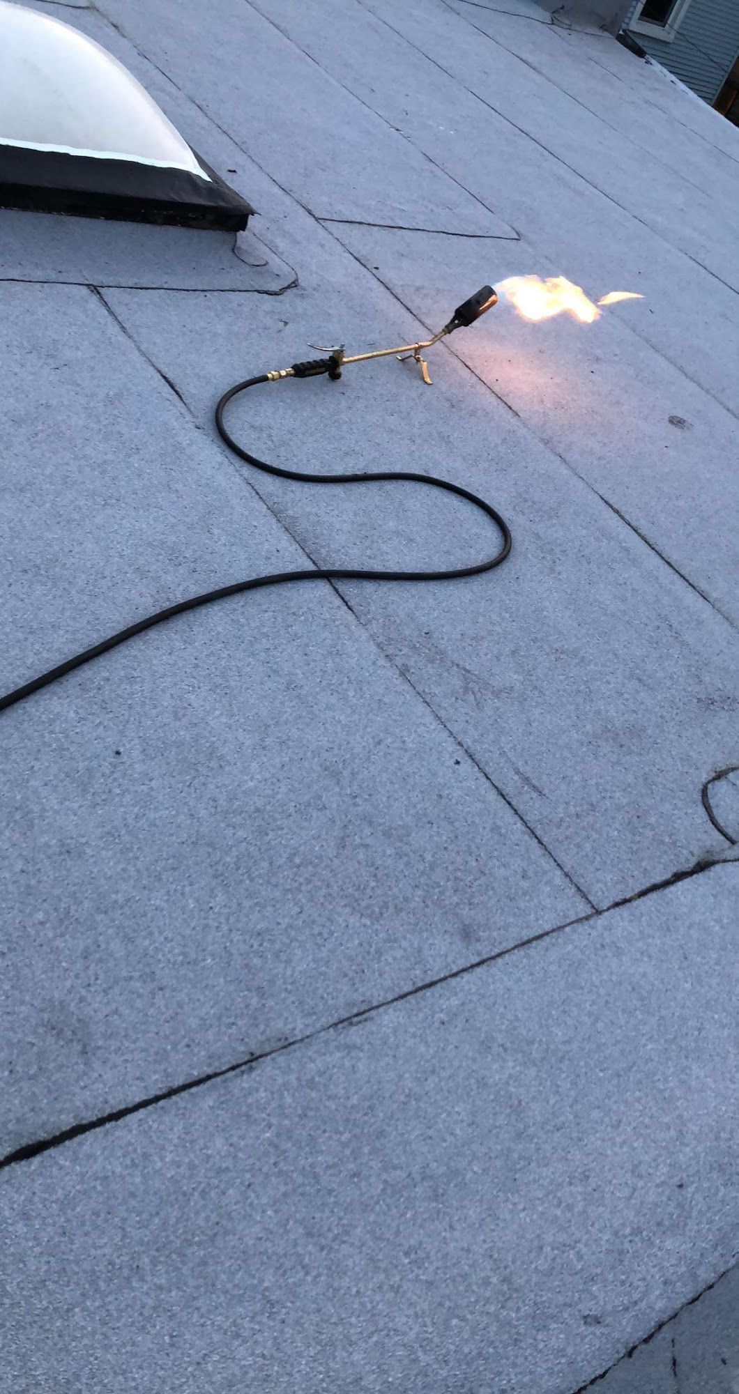 Torch flame on a cable lying across a gray shingled roof.