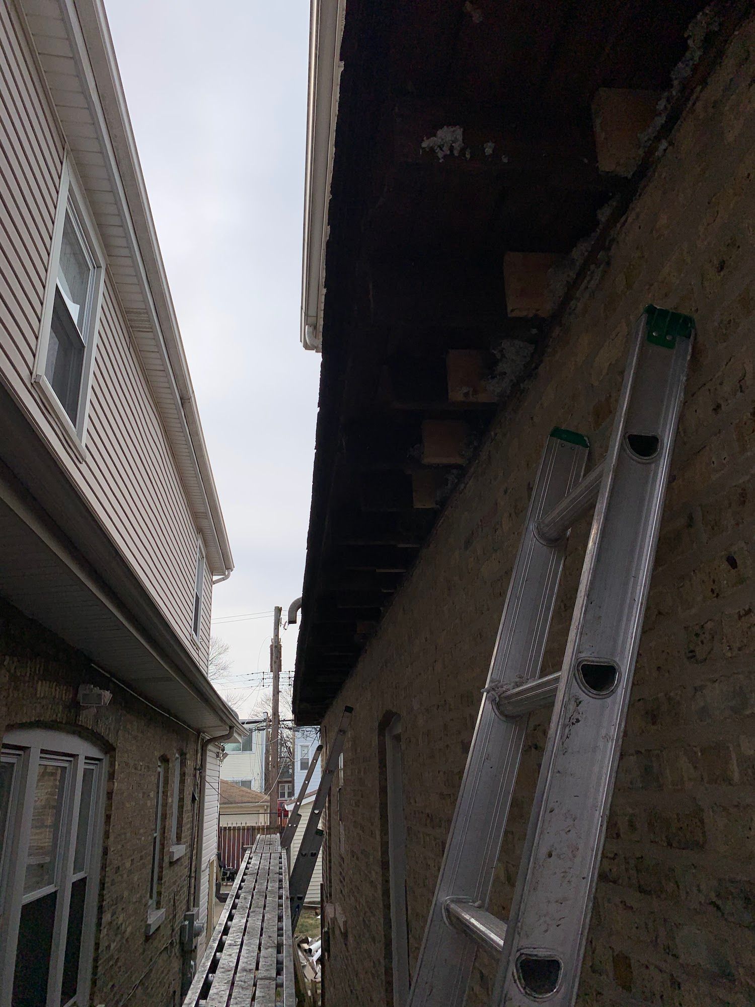 Narrow alley between buildings with a ladder leaning against the right wall.