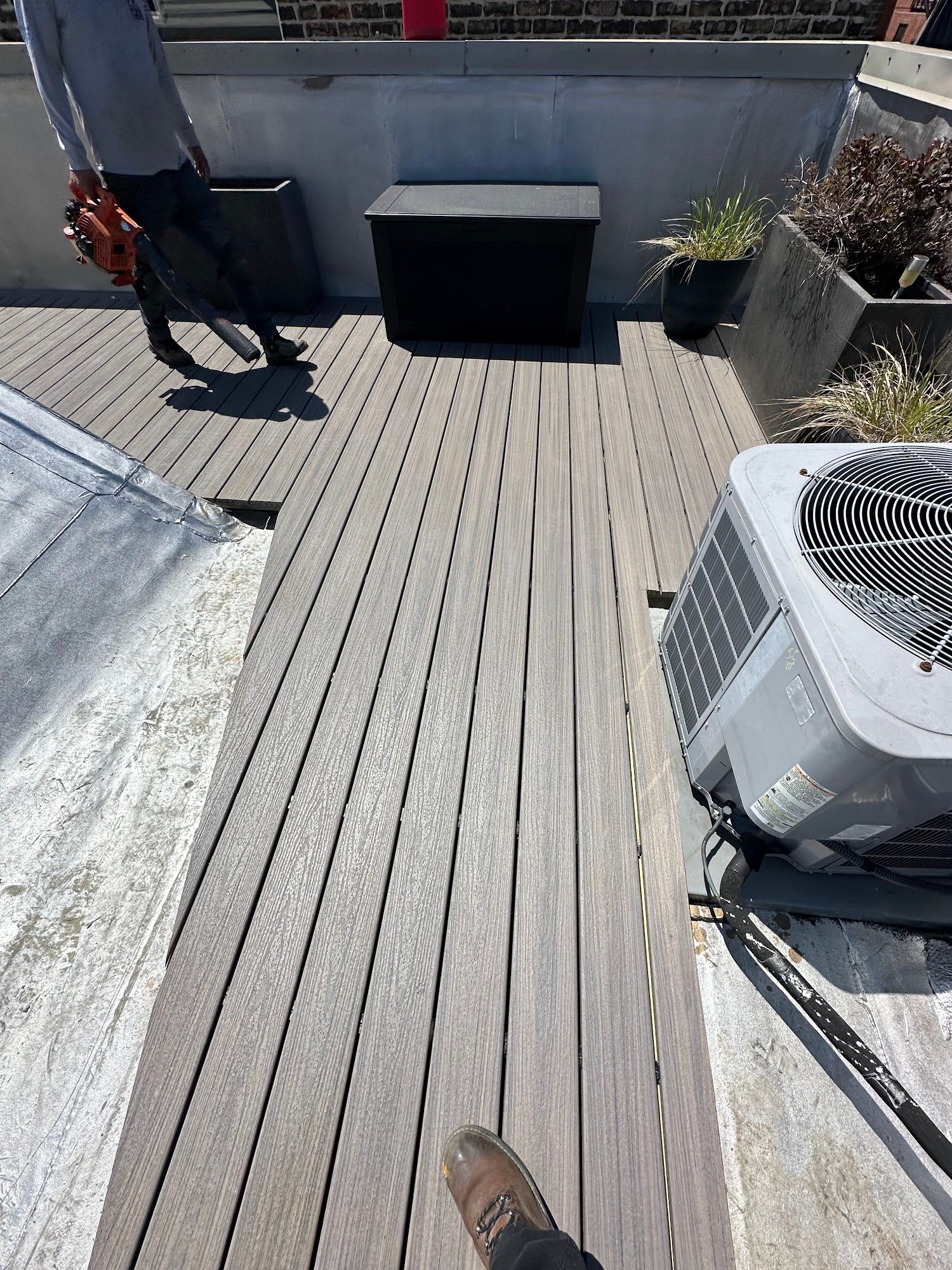 Rooftop deck with gray composite flooring, planter boxes, and an outdoor AC unit.